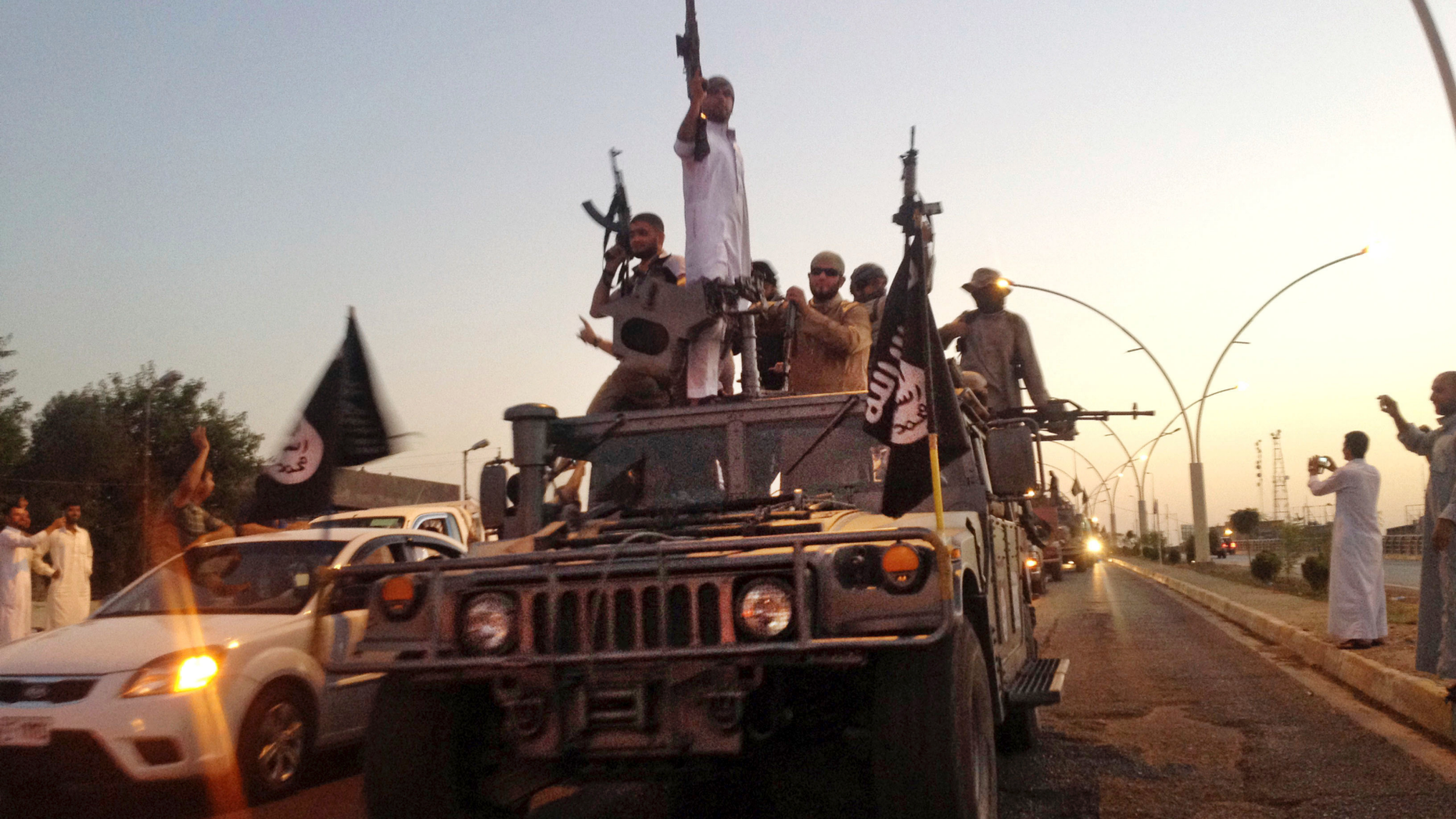 FILE - In this June 23, 2014 file photo, fighters from the Islamic State group parade in a commandeered Iraqi security forces armored vehicle in the northern city of Mosul, Iraq. In a report issued Thursday, Dec. 13, 2018, the New York-based rights group Amnesty International said the IS group’s deliberate destruction of agriculture in northern Iraq has hindered the return of hundreds of thousands of residents. The rights group said IS fighters burnt or chopped down orchards, sabotaged wells and stole or destroyed vital farming equipment. (AP Photo, File)