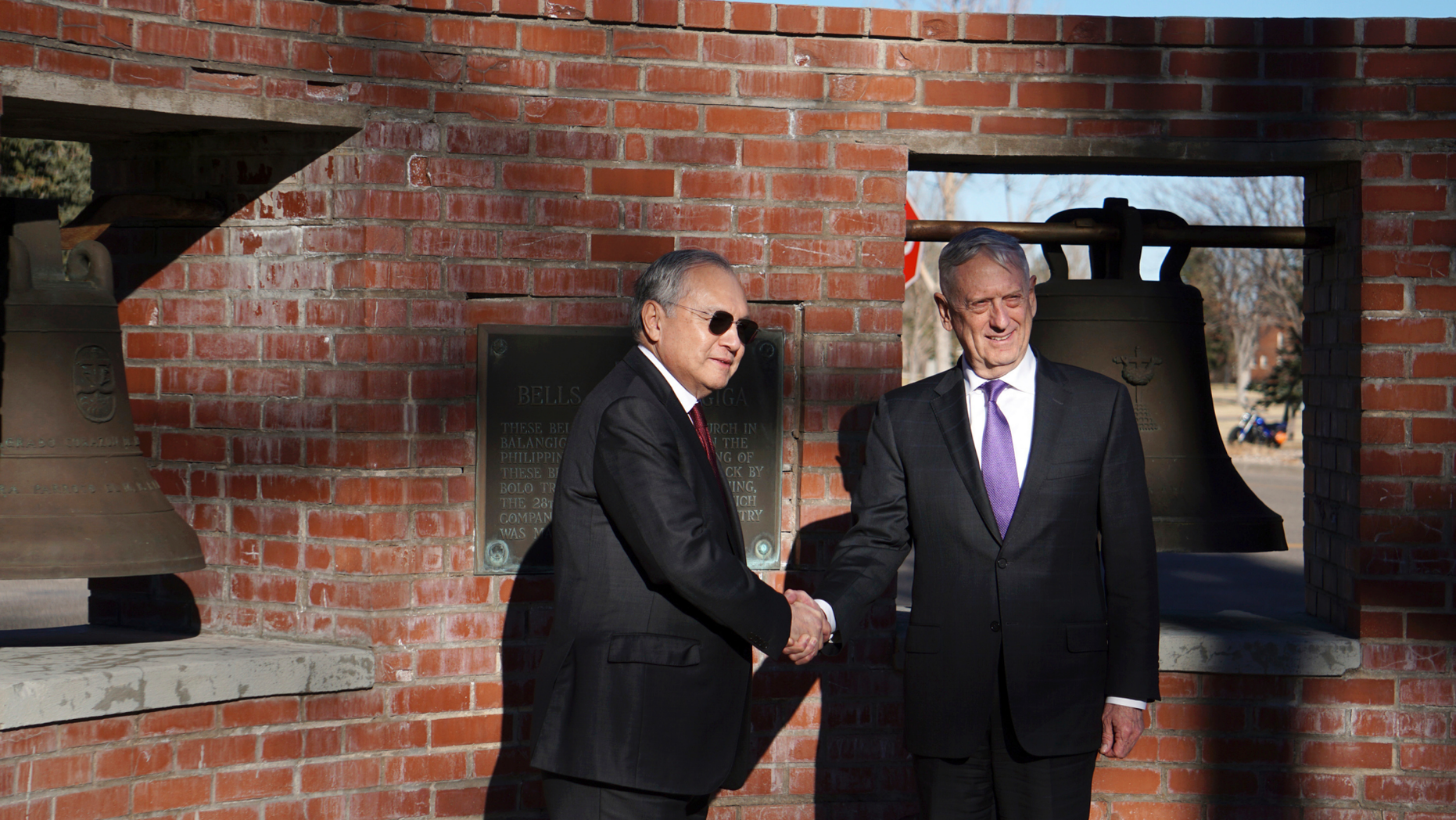 FILE - In this Nov. 14, 2018, file photo, Philippine ambassador to the U.S., Jose Manuel Romualdez, left, and U.S. Defense Secretary James Mattis shake hands at two of the Bells of Balangiga at F.E. Warren Air Force Base in Cheyenne, Wyoming. Three church bells seized by American troops as war trophies more than a century ago arrived in Manila on Tuesday, Dec. 11, 2018 to be handed back to the Philippines in a move long demanded by Filipino leaders, including the current president, who is critical of Washington and has moved closer to China. (AP Photo/Mead Gruver, File)