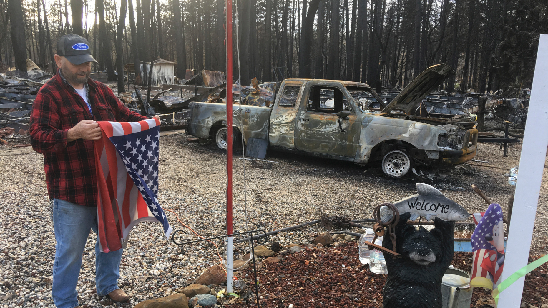 Jerry McLean folds the flag that was flying outside the remains of his home Wednesday, Dec. 5, 2018, in Paradise, Calif. Some residents of a California town devastated by a catastrophic wildfire nearly a month ago were finally allowed to return home to sift through the charred remains in search of precious family heirlooms, photos and other possessions. (AP Photo/Don Thompson)
