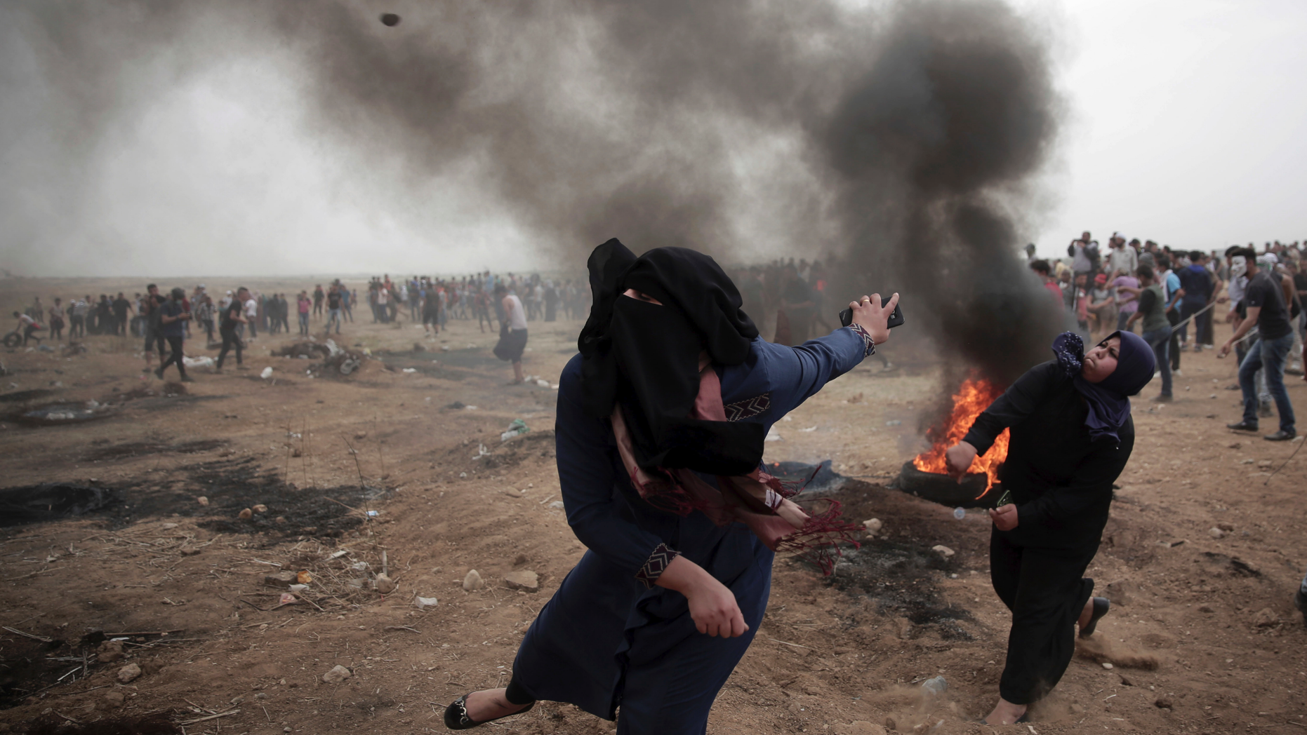 Palestinian women hurl stones at Israeli troops during a protest at the Gaza Strip's border with Israel on May 4, 2018. (AP Photo/ Khalil Hamra)