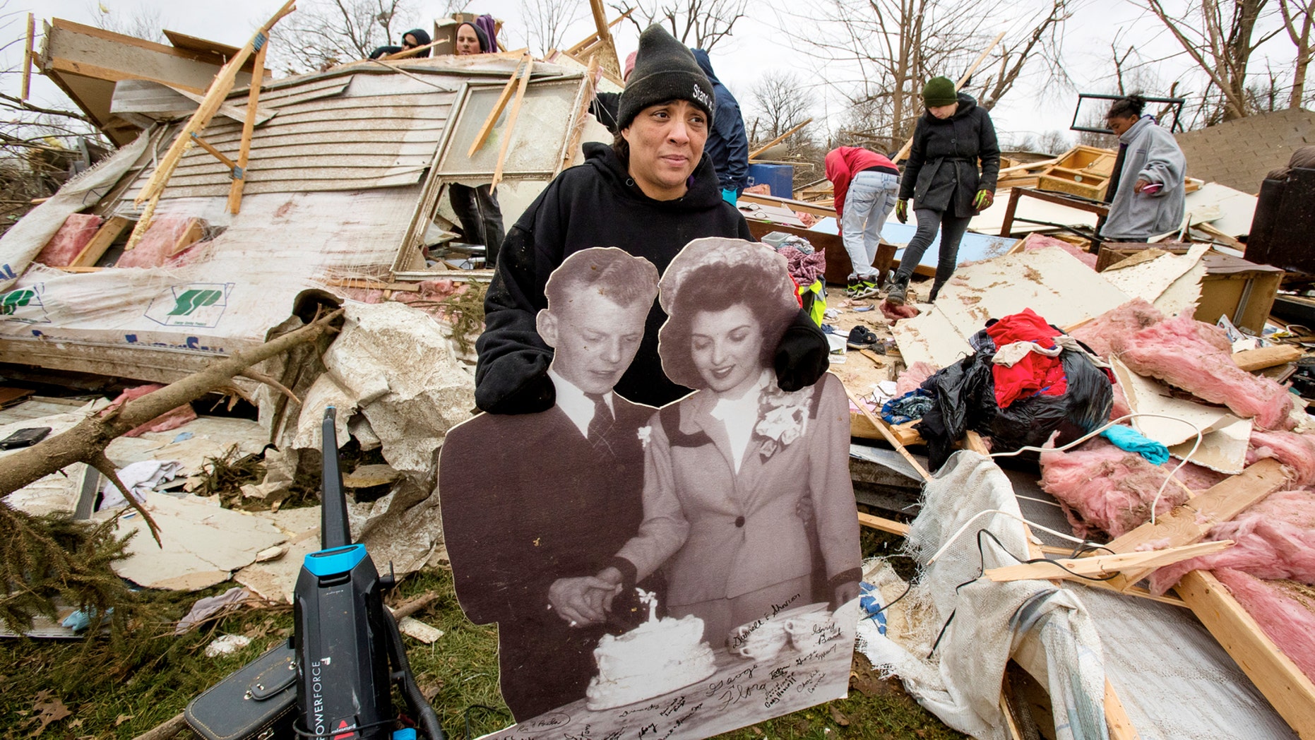 Tiffani Bailey carries an enlarged wedding photo of her grandparents, Charles and Betty Bailey, from the debris of her destroyed home in Taylorville. Bailey, who was in the trailer with her son and mom when it was hit, damaged her ribs and needed more than 30 stitches. "It's a miracle I'm alive. I was in this trailer when it got hit. I lost everything, though. I got nothing," she said. (Ted Schurter/The State Journal-Register via AP)