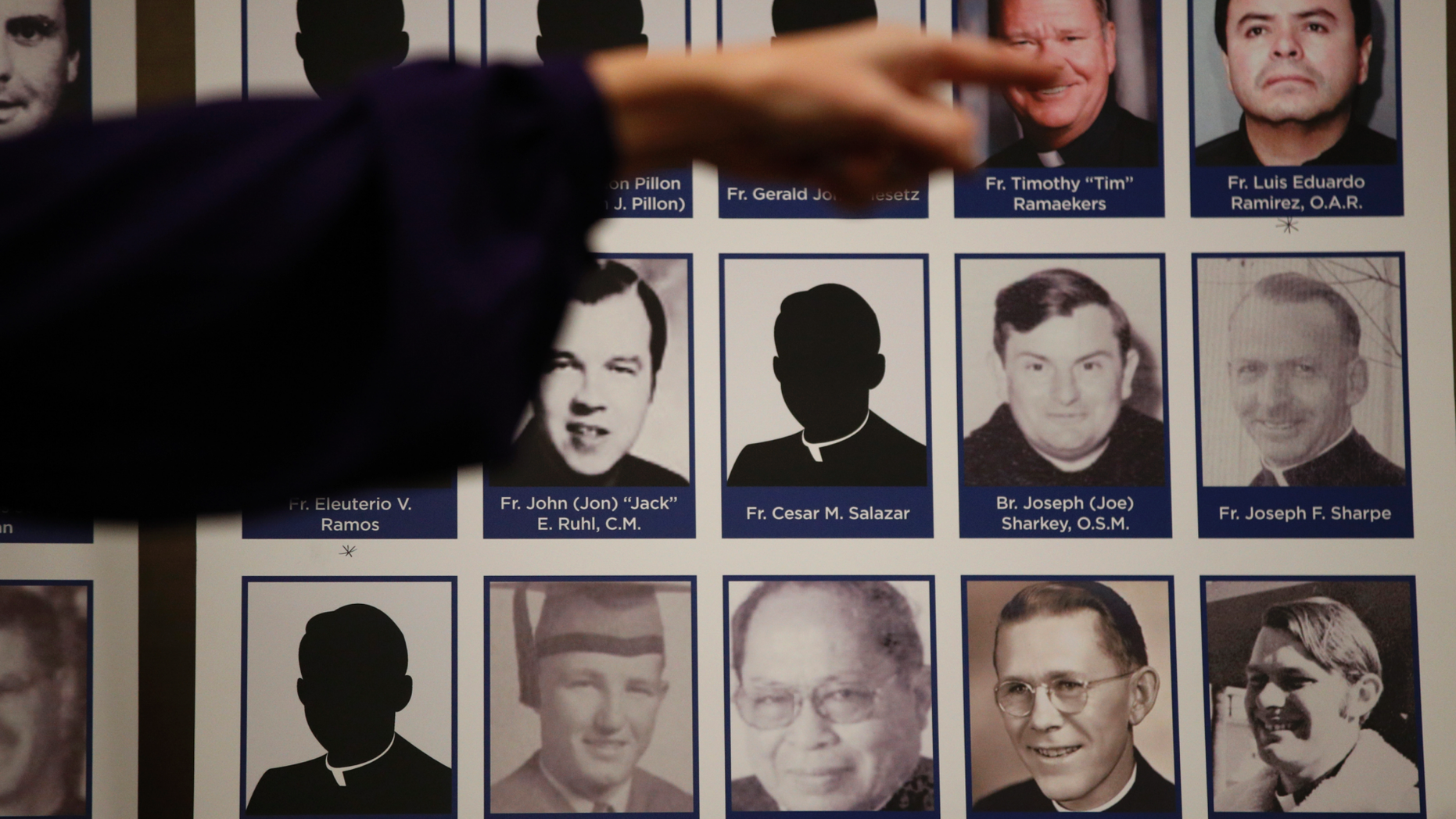 An advocate and survivor of sexual abuse, points to the photos of Catholic priests accused of sexual misconduct by victims during a news conference Thursday, Dec. 6, 2018, in Orange, Calif. Lawyer Mike Reck on Thursday said that's many more than those reported by the Diocese and demanded greater transparency. The Diocese of Orange says the lawyers are trying to re-litigate old claims that the church takes any accusations of abuse "extraordinarily seriously." (AP Photo/Jae C. Hong)