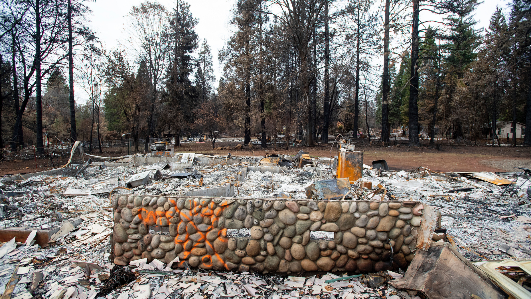 An exterior wall stands in front of the burned home of Patrick Holden and Nancy Barnes, Monday, Dec. 3, 2018, in Paradise, Calif. Holden and Barnes were listed as missing but are actually vacationing in Hawaii. (AP Photo/Noah Berger)