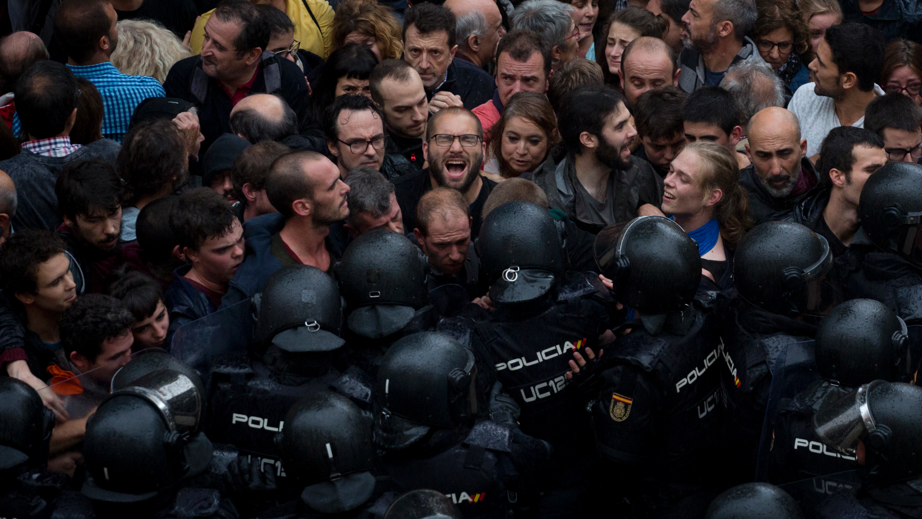 FILE - In this Oct. 1, 2017 file photo, Spanish national police block people trying to reach a voting site at a school assigned to be a polling station by the Catalan government for a secession referendum in Barcelona, Spain. Spain’s central government threatened on Tuesday, Dec. 11, 2018, to send in national police to ensure security in Catalonia if regional authorities fail to stop recent disruptions by pro-independence protesters on major highways. (AP Photo/Emilio Morenatti, File)