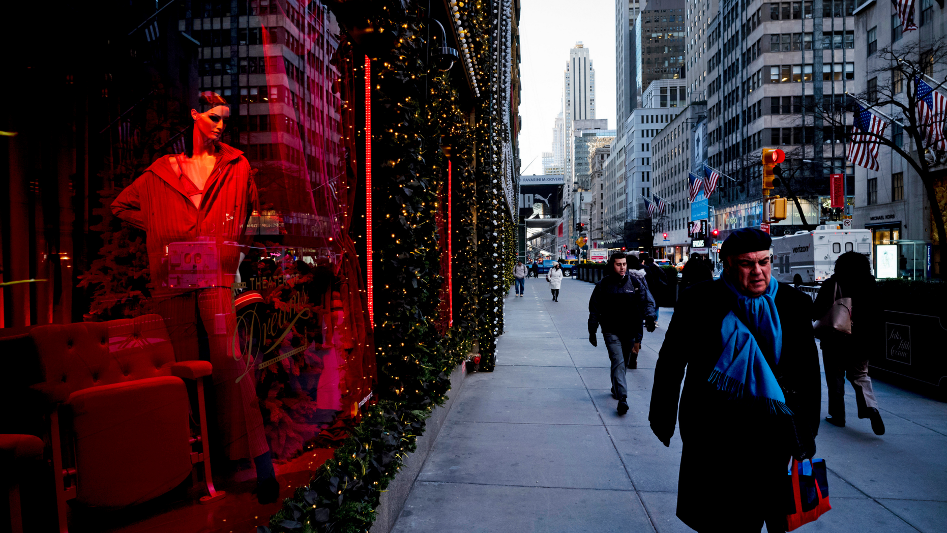 FILE - In this Wednesday, Dec. 5, 2018 file photo, people walk past a holiday window at Saks Fifth Avenue, in New York. U.S. consumer confidence tumbled this month as Americans began to worry that economic growth will moderate next year. The Conference Board, a business research group, says its consumer confidence index fell to 128.1 in December, down from 136.4 in November and lowest since July. (AP Photo/Mark Lennihan, File)