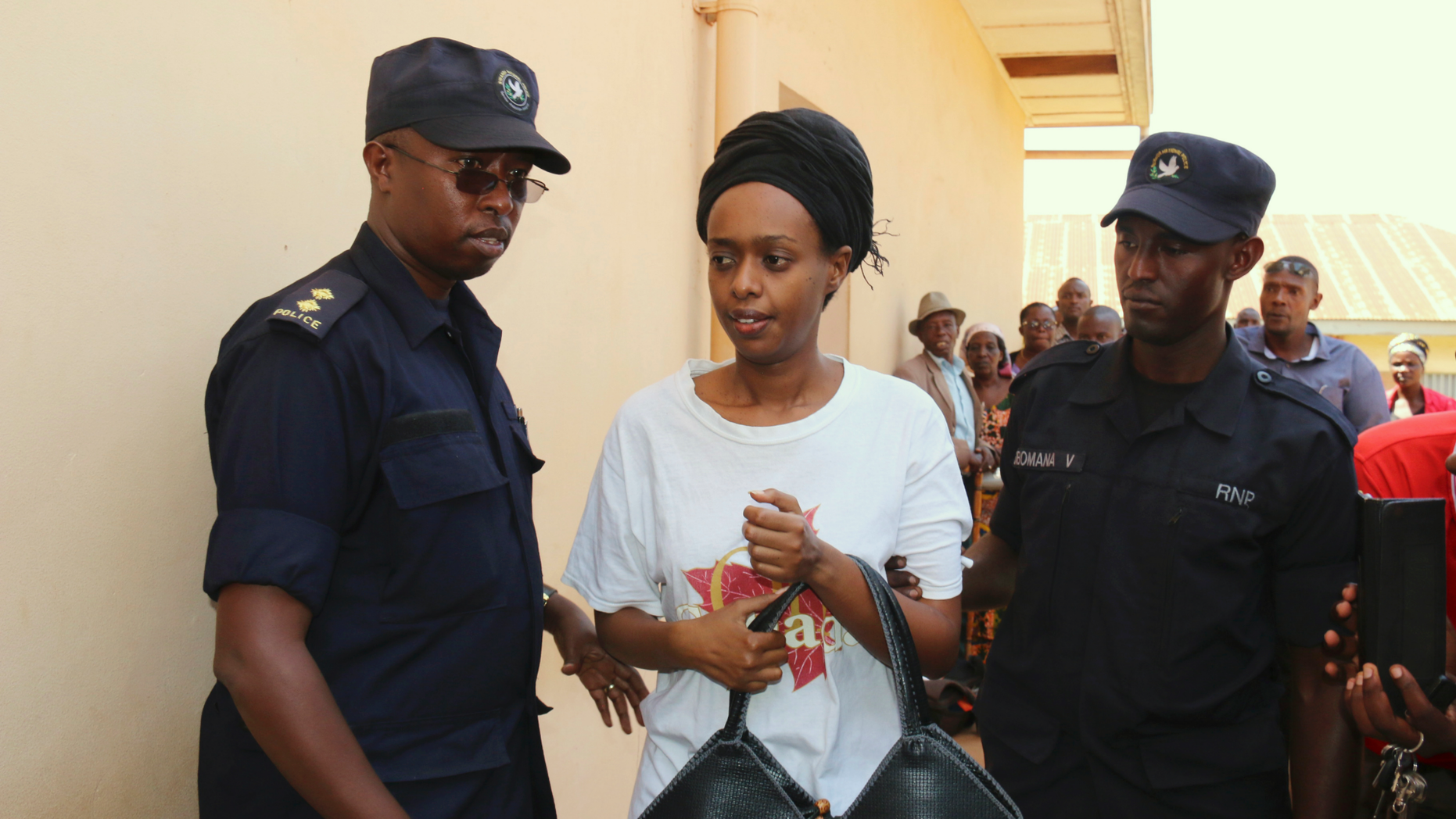 FILE - In this Friday, Oct. 6, 2017 file photo, former Rwanda presidential candidate Diane Rwigara is escorted by policemen to a court where she denied charges of insurrection and forgery that she says are linked to her criticism of the government's human rights record. As she waits for a judge to pronounce her fate on Thursday, Dec. 6, 2018, the Rwandan opposition leader accused of inciting insurrection and forgery says no amount of pressure will silence her. (AP Photo, File)
