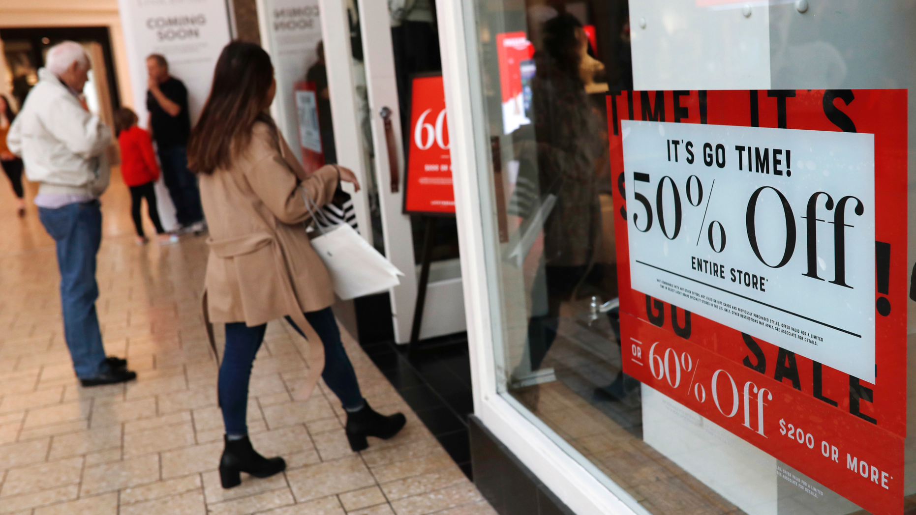 FILE - In this Dec. 24, 2018, file photo, discount placards stand in the window of a clothing store as last-minute shoppers finish up their Christmas gift lists at the Cherry Creek Mall in Denver. Americans buoyed by a strong economy pushed holiday sales growth to a six-year high. (AP Photo/David Zalubowski, File)