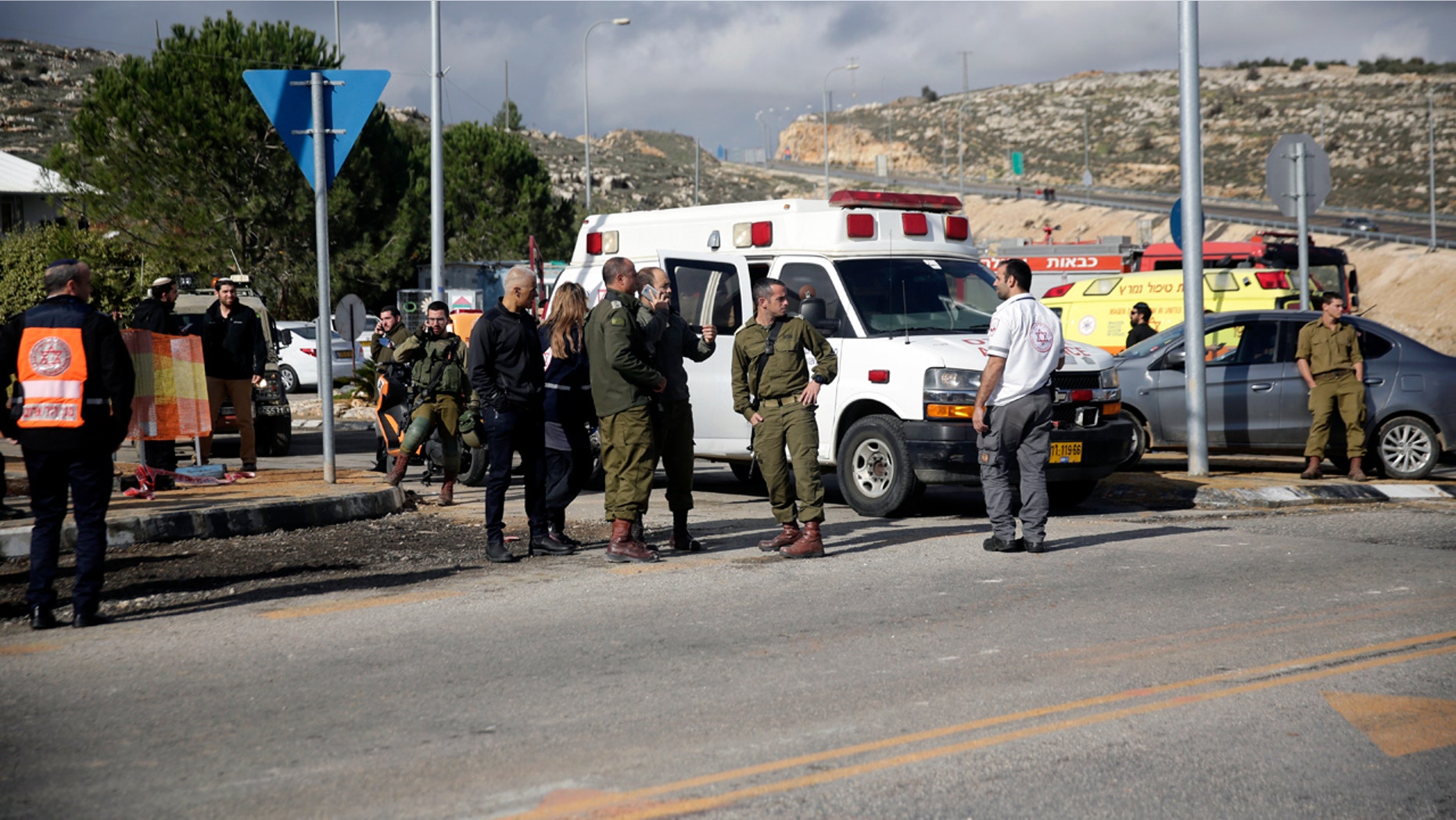 Israeli soldiers stand at the scene of an attack near the settlement of Givat Assaf in the West Bank, Thursday, Dec. 13, 2018. A Palestinian gunman opened fire at a bus stop outside a West Bank settlement on Thursday, shooting at soldiers and civilians and killing at least two Israelis before fleeing, the military and Israel's rescue service said. (AP Photo/Mahmoud Illean)