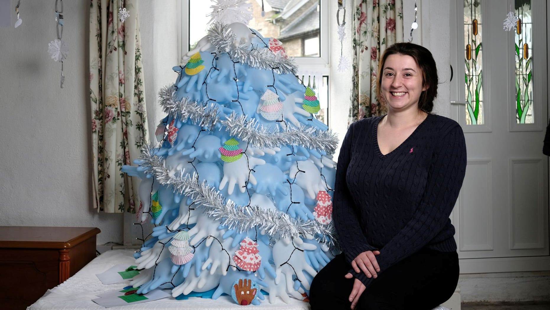 Maxine Oliver poses with her Christmas tree — made for about $2.50 from surgical gloves.