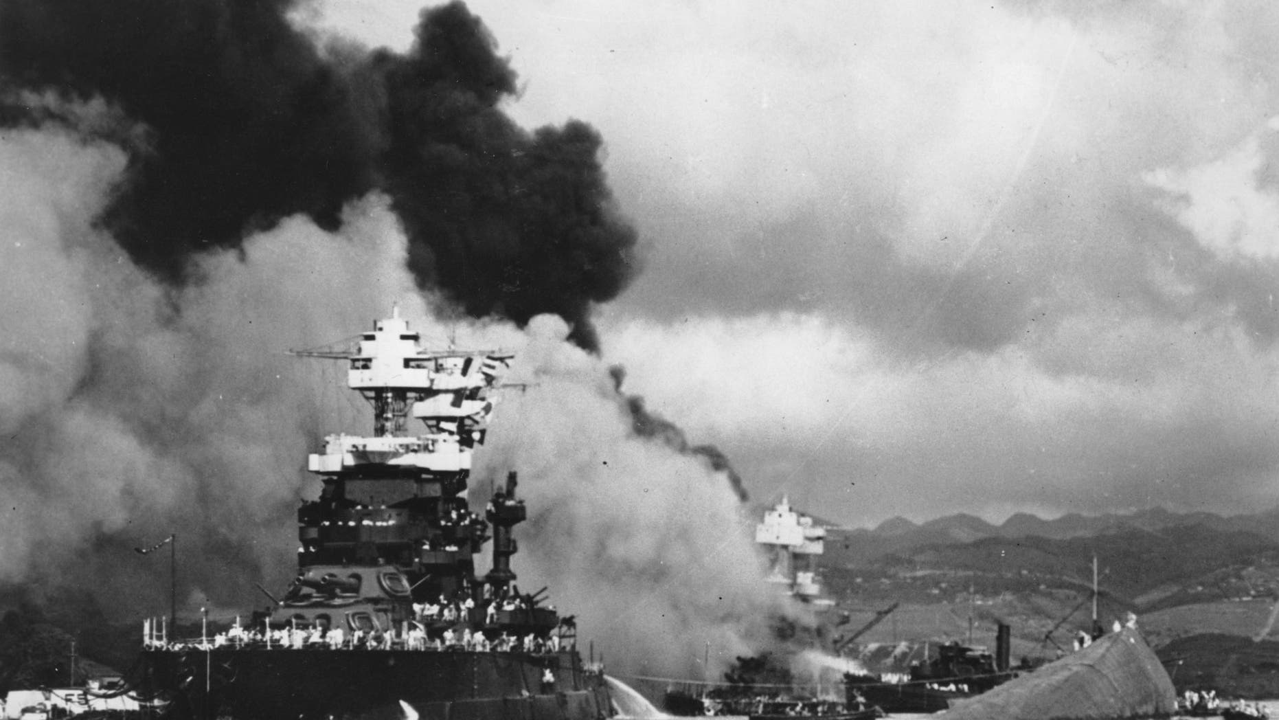 In this Dec. 7, 1941 file photo, part of the hull of the capsized USS Oklahoma is seen at right as the battleship USS West Virginia, center, begins to sink after suffering heavy damage, while the USS Maryland, left, is still afloat in Pearl Harbor, Oahu, Hawaii.
