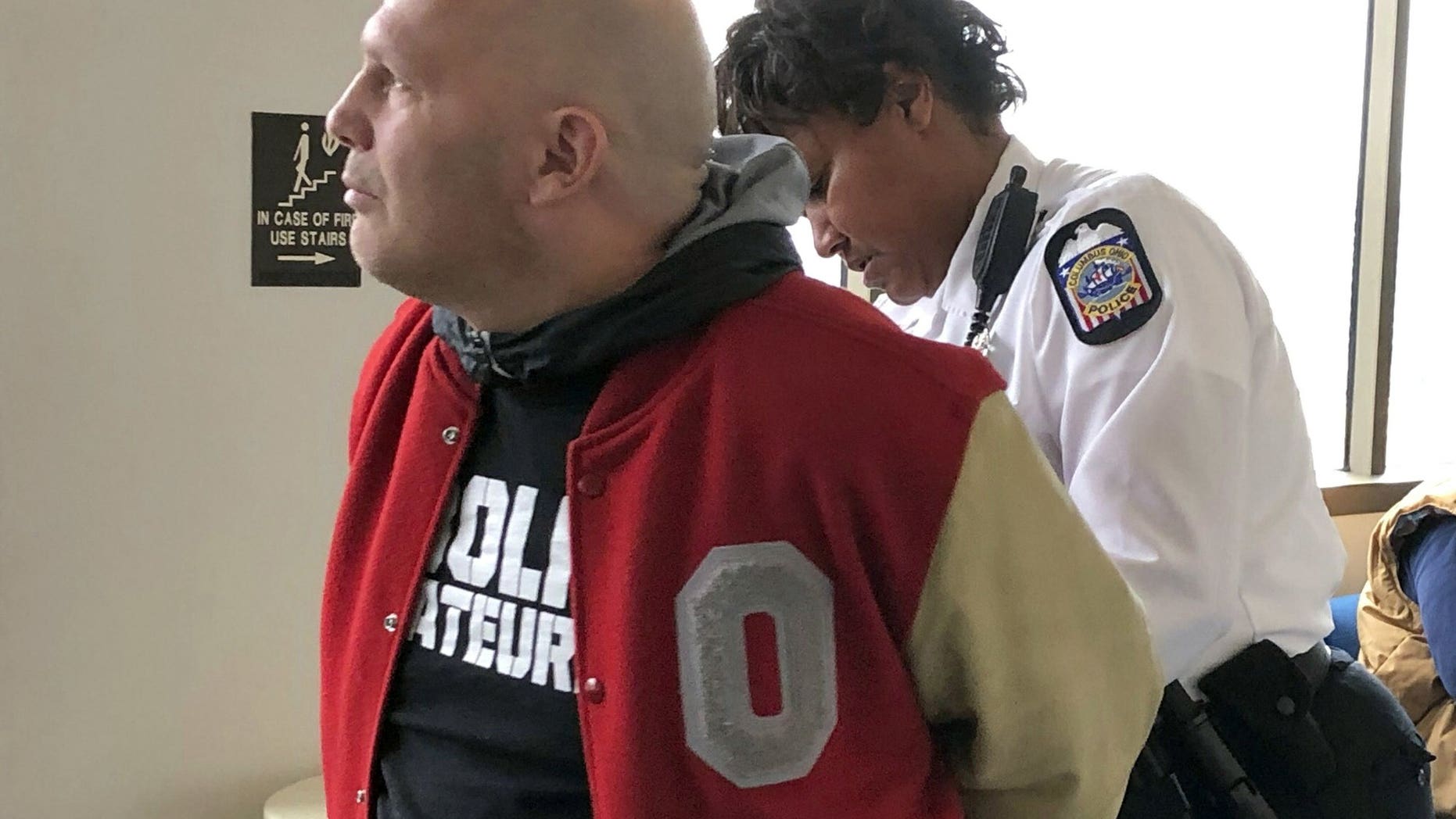 Mike DiSabato, left, turns himself in for arrest by an officer at Franklin County Municipal Court in Columbus, Ohio, on Monday, Jan. 7, 2019.
