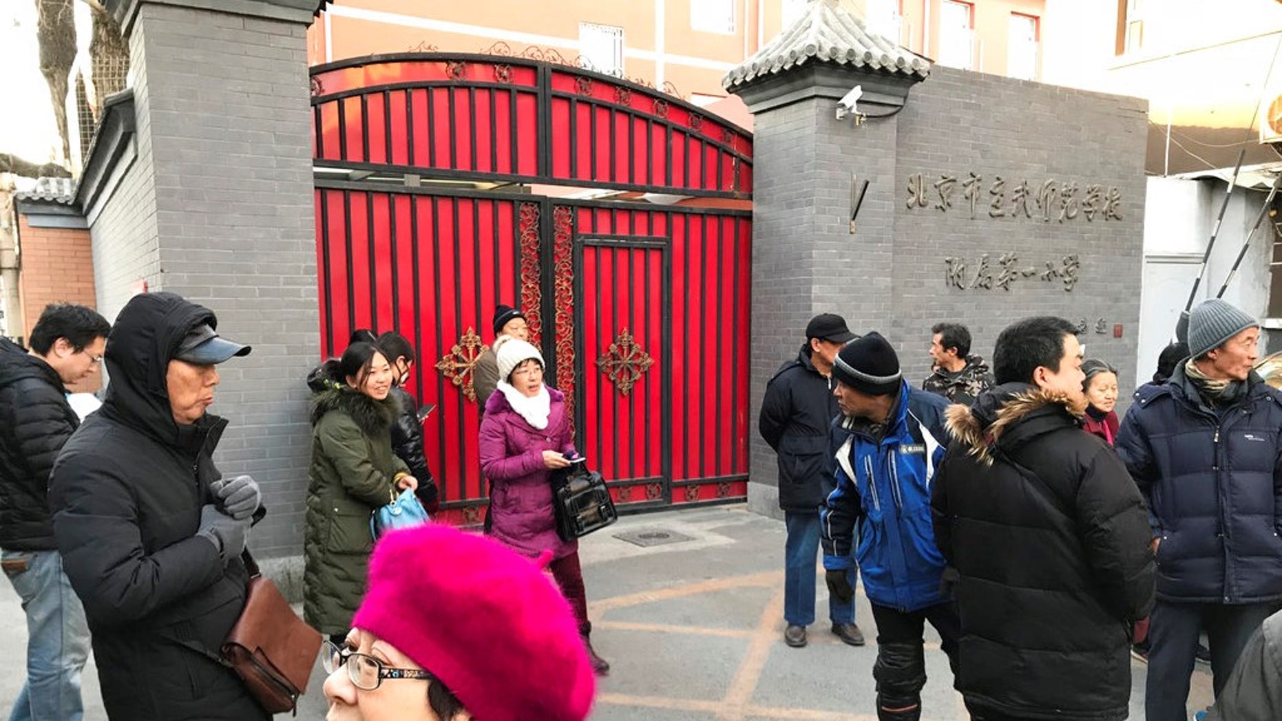 Parents gather at an entrance gate to the Beijing No. 1 Affiliated Elementary School of Xuanwu Normal School following an attack in Beijing, China, Tuesday, Jan. 8, 2019.