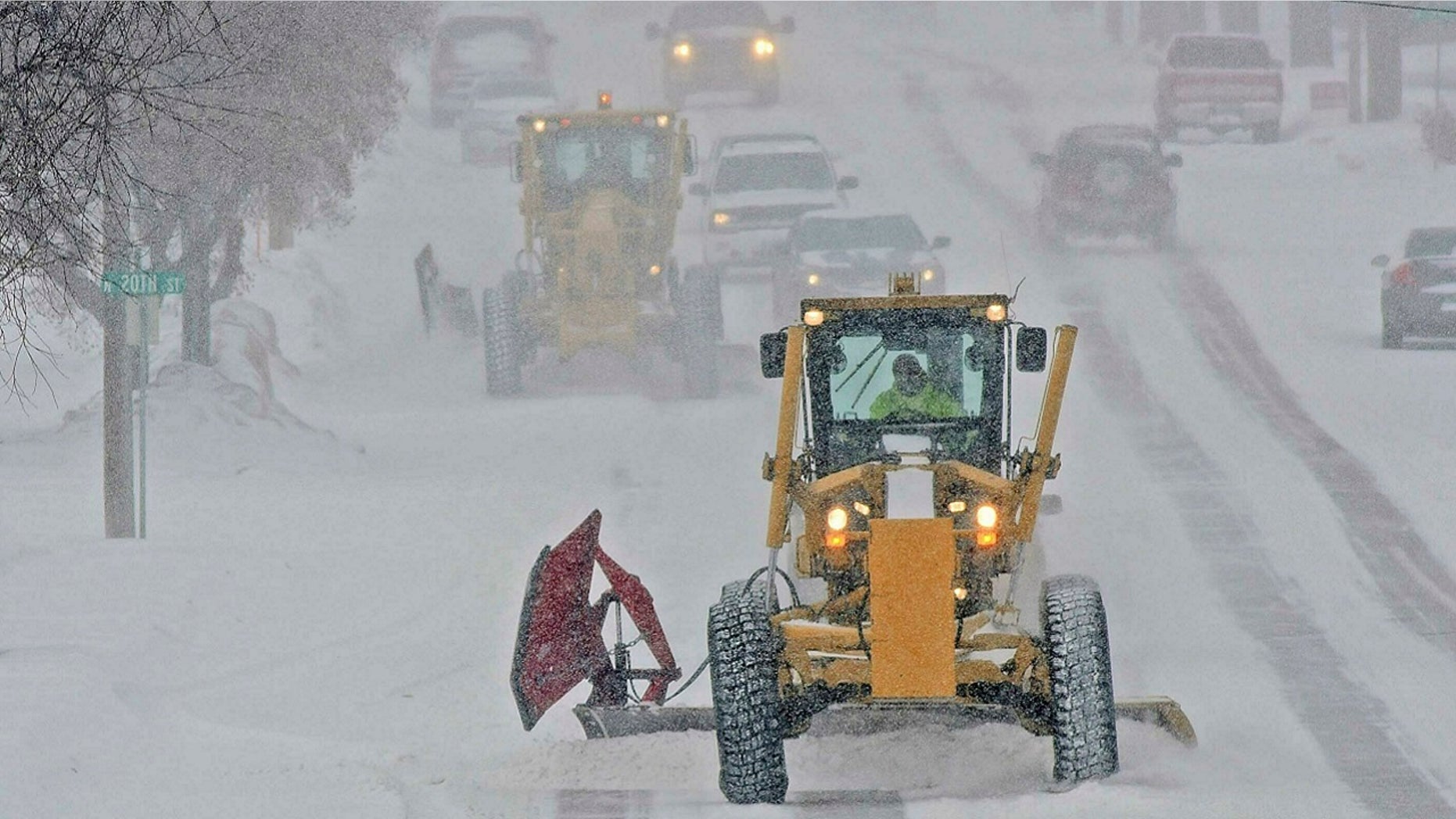 Motor graders plow Rosser Avenue as snow falls, Friday, Jan. 18, 2019, in Bismarck, N.D.