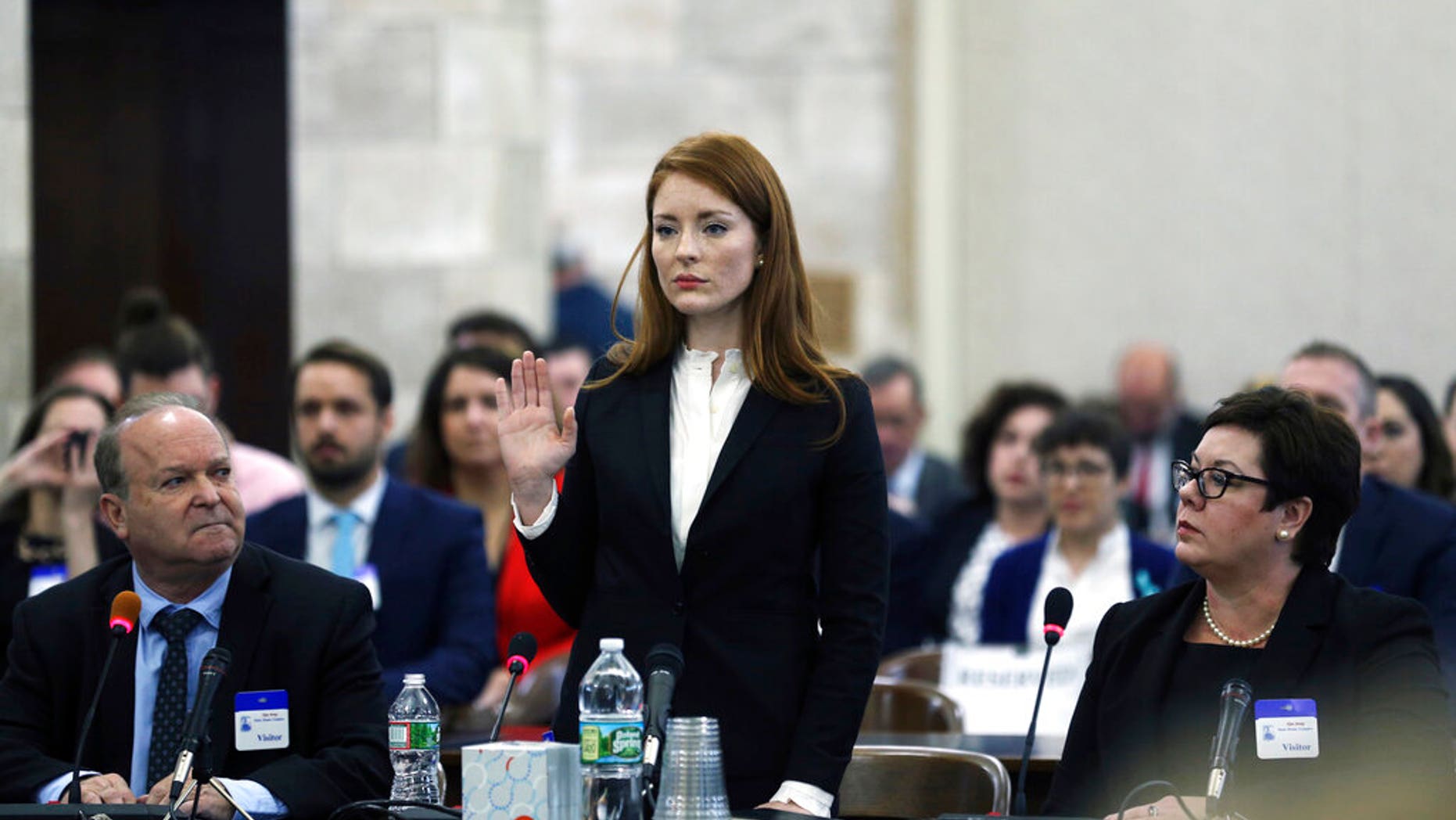FILE- In this Dec. 4, 2018, file photo, Katie Brennan, the chief of staff at the New Jersey Housing and Mortgage Finance Agency, raises her hand as she is sworn in to testify before the Select Oversight Committee at the Statehouse, in Trenton, On Wednesday, the Middlesex County Prosecutor's office said that it would not be filing charges against Albert Alvarez, whom Brennan accused of sexually assaulting her in 2017, when they were both working to get Gov. Phil Murphy elected, citing "a lack of credible evidence." (AP Photo/Mel Evans, File)