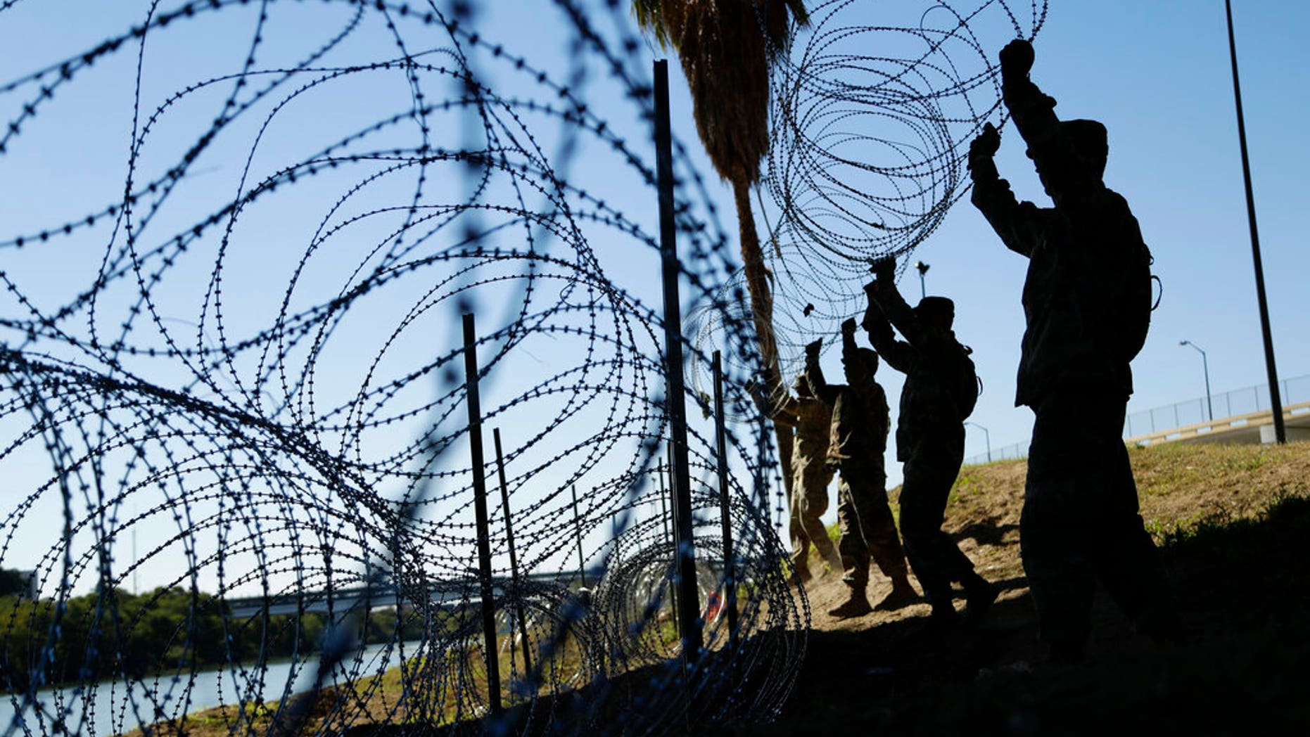 In this Nov. 16, 2018, file photo, members of the U.S. military install multiple tiers of concertina wire along the banks of the Rio Grande near the Juarez-Lincoln Bridge at the U.S.-Mexico border in Laredo, Texas. (AP Photo/Eric Gay, File)