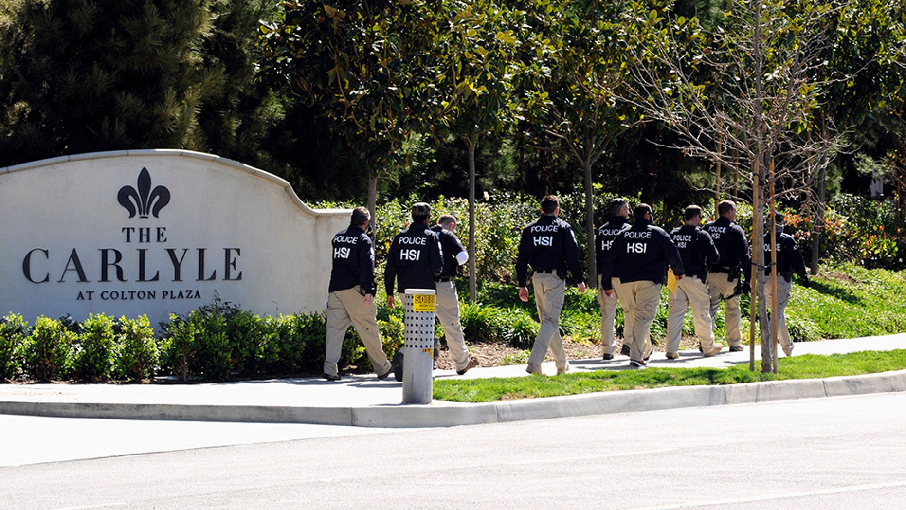 Federal agents walk past Carlyle Apartments, a location suspected of involvement in "maternity tourism" schemes, in Irvine March 3, 2015. (REUTERS/Bob Riha Jr.)