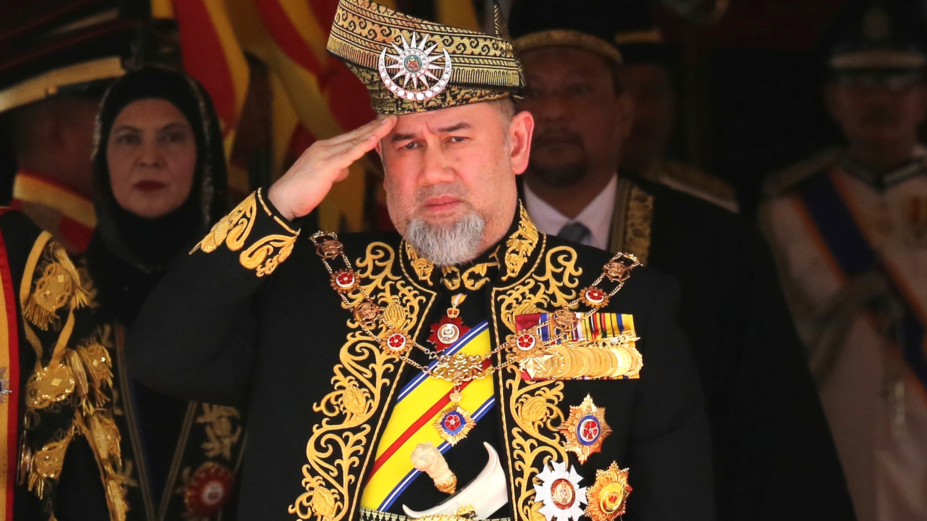 FILE - In this July 17, 2018, file photo, Malaysian King Sultan Muhammad V salutes during the national anthem at the opening of the 14th parliament session at the Parliament house in Kuala Lumpur, Malaysia. Malaysia King Sultan Muhammad V has abdicated in an unexpected and rare move, just after two years on the throne. The palace said in a statement on Sunday, Jan. 6, 2019, that Sultan Muhammad V, 49, has resigned with immediate effect, cutting short his five-year term, without giving any reasons. Sultan Muhammad V, ruler of northeast Kelantan state, was installed in December 2016 as one of the country's youngest constitutional monarchs. (AP Photo/Yam G-Jun, File)