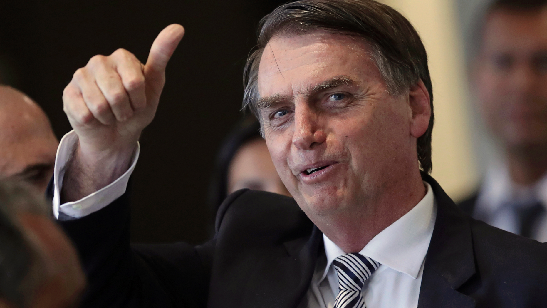 FILE - In this Dec. 4, 2018 file photo, Brazil's President-elect Jair Bolsonaro gives a thumbs up as he leaves his transition headquarters in Brasilia, Brazil. Bolsonaro will take office on Jan. 1. (AP Photo/Eraldo Peres)