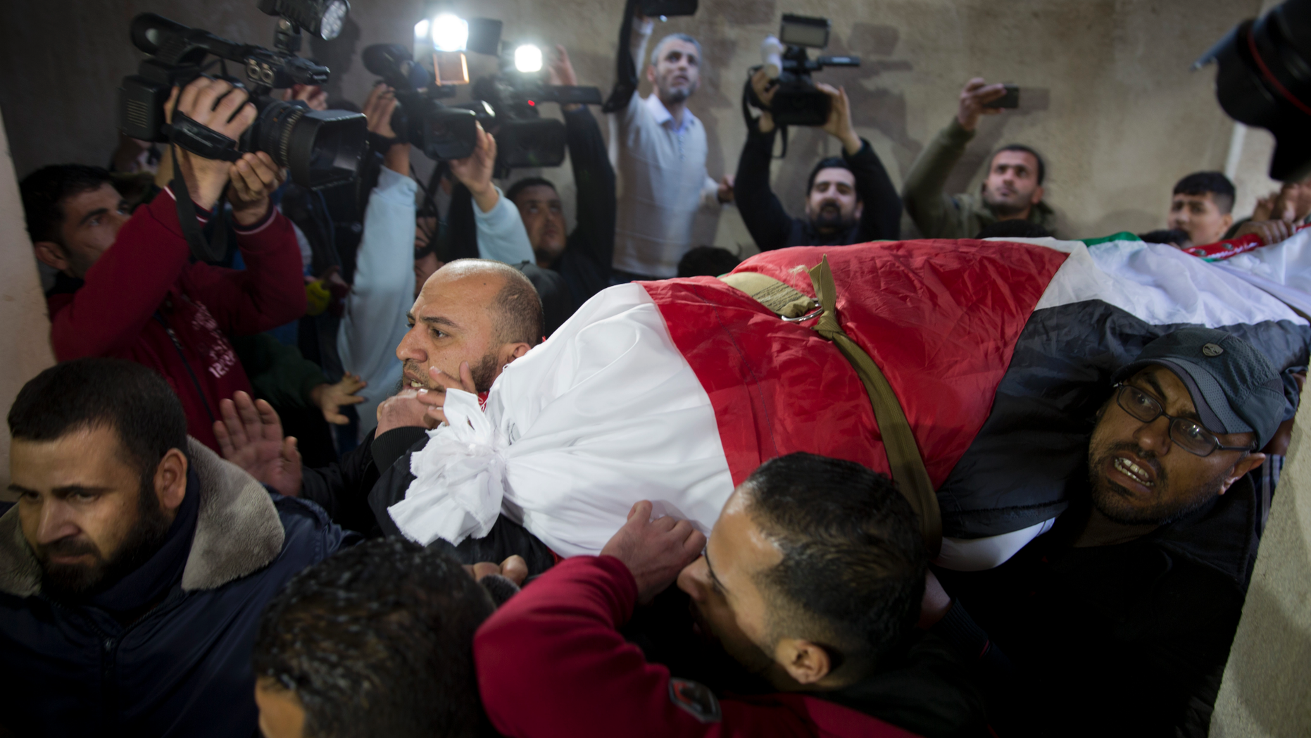 Mourners carry the body of Palestinian woman, Amal al-Taramsi, 43, who was killed by Israeli troops during Friday's protest at the Gaza Strip's border with Israel, into the family home during her funeral in Gaza City, Saturday, Jan. 12. (AP Photo/Khalil Hamra)