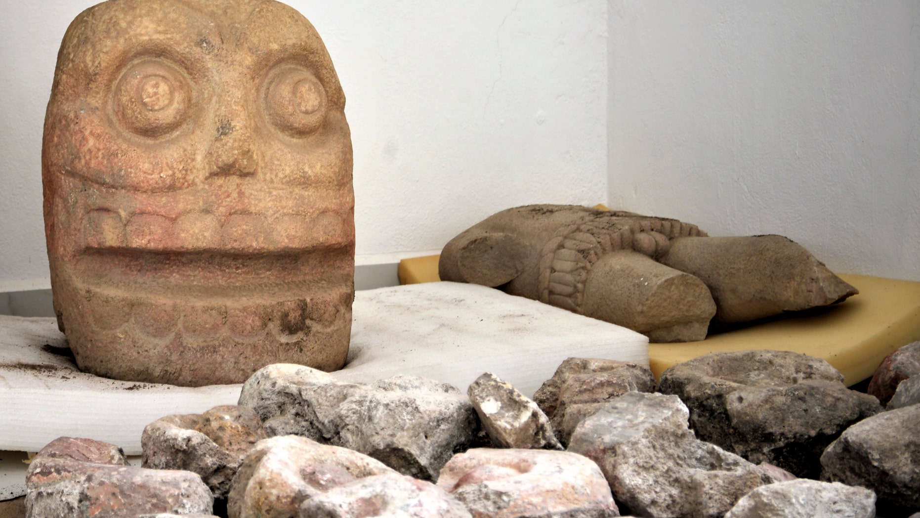 In this 2018 photo provided by Mexico's National Institute of Anthropology and History, INAH, a skull-like stone carving and a stone trunk depicting the Flayed Lord, a pre-Hispanic fertility god depicted as a skinned human corpse, are stored after being excavated. (Meliton Tapia Davila/INAH via AP)