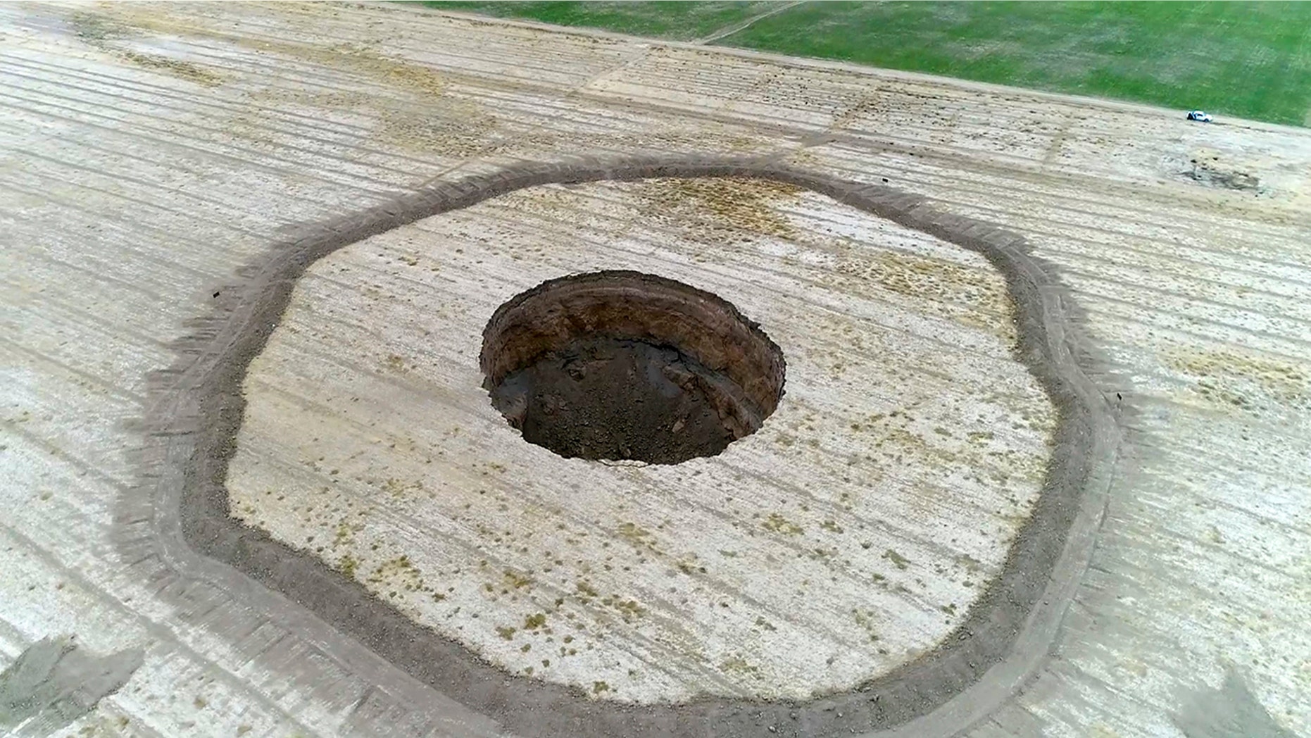 This frame grab from an Aug. 8, 2018 video provided by Iranian Students' News Agency, ISNA, shows an aerial view of a massive hole caused by drought and excessive water pumping in Kabudarahang, in Hamadan province, in western Iran. Some sinkholes formed in western Iran are as deep as 196 feet.
