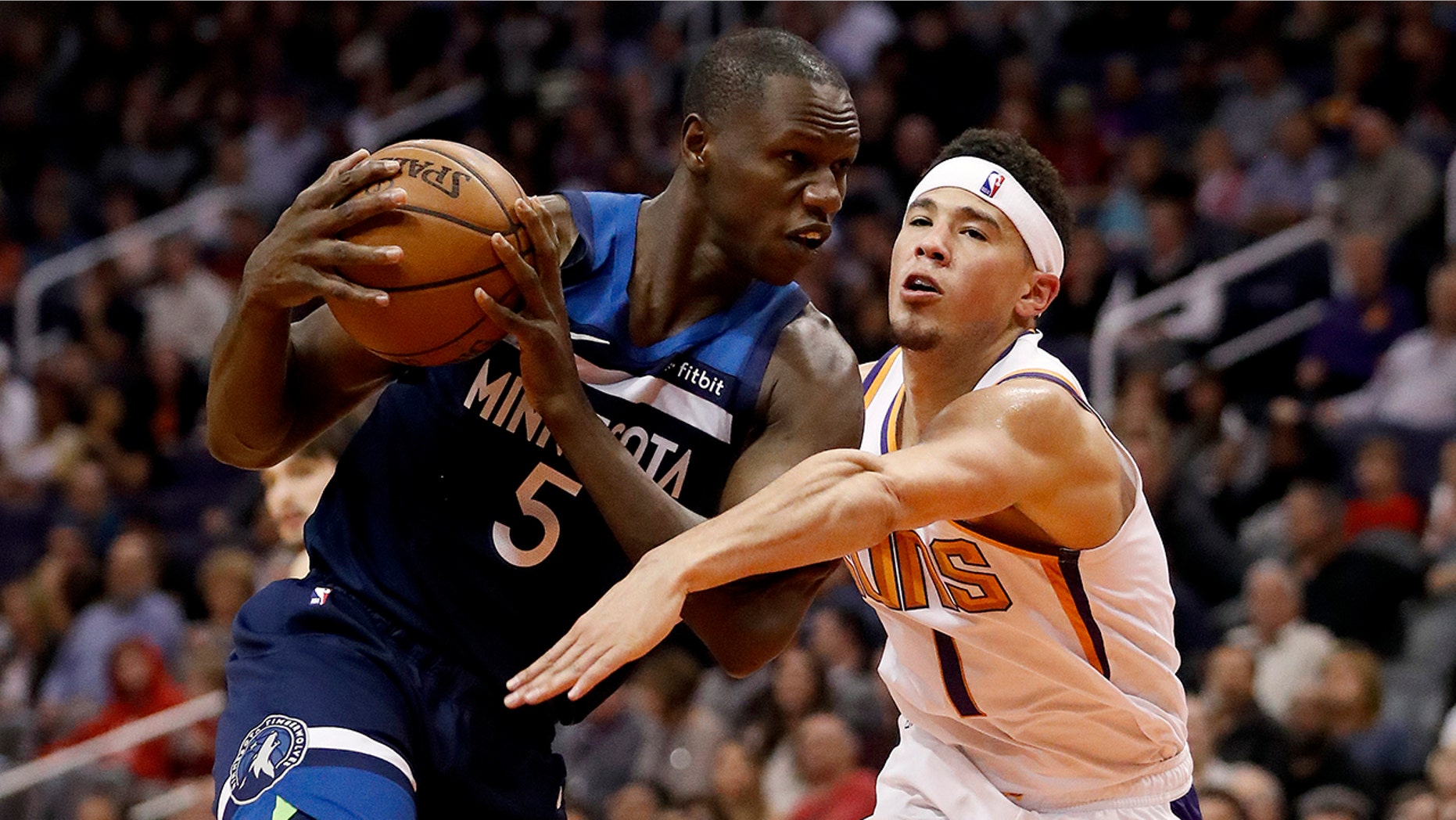 Minnesota Timberwolves center Gorgui Dieng (5) takes the ball away from Phoenix Suns guard Devin Booker (1) during the second half of an NBA basketball game, Tuesday, Jan. 22, 2019, in Phoenix. The Timberwolves won 118-91.