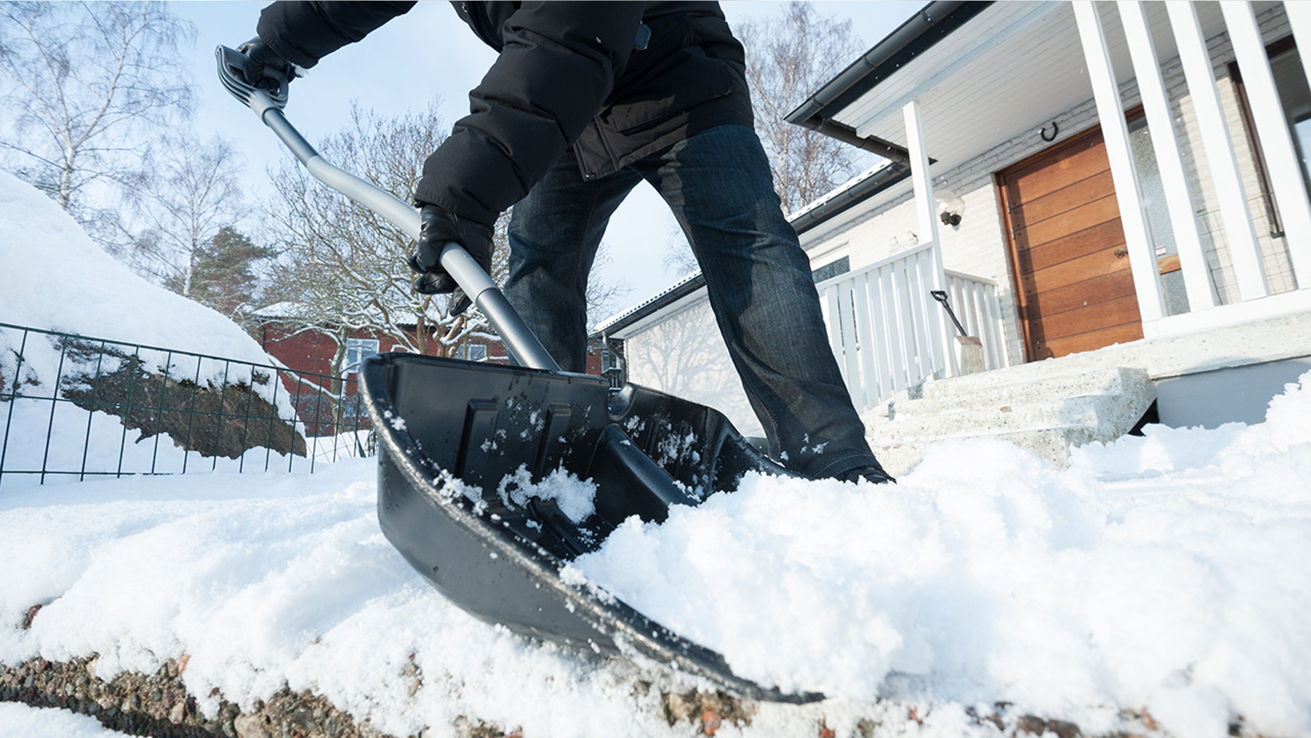 Man removing snow with a snow shovel in front of his house.