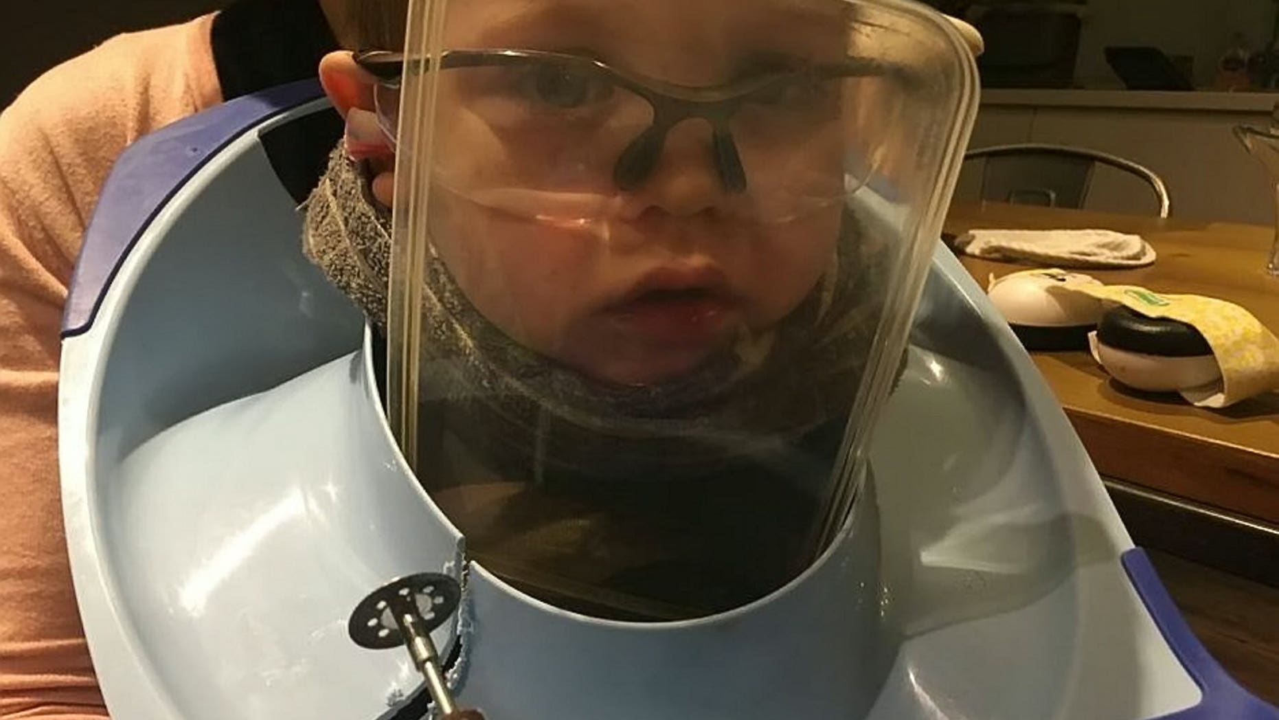 The tiny tot dons protective equipment as Avon Fire and Rescue use a Dremel spinning disc cutter to free him from his potty prison.