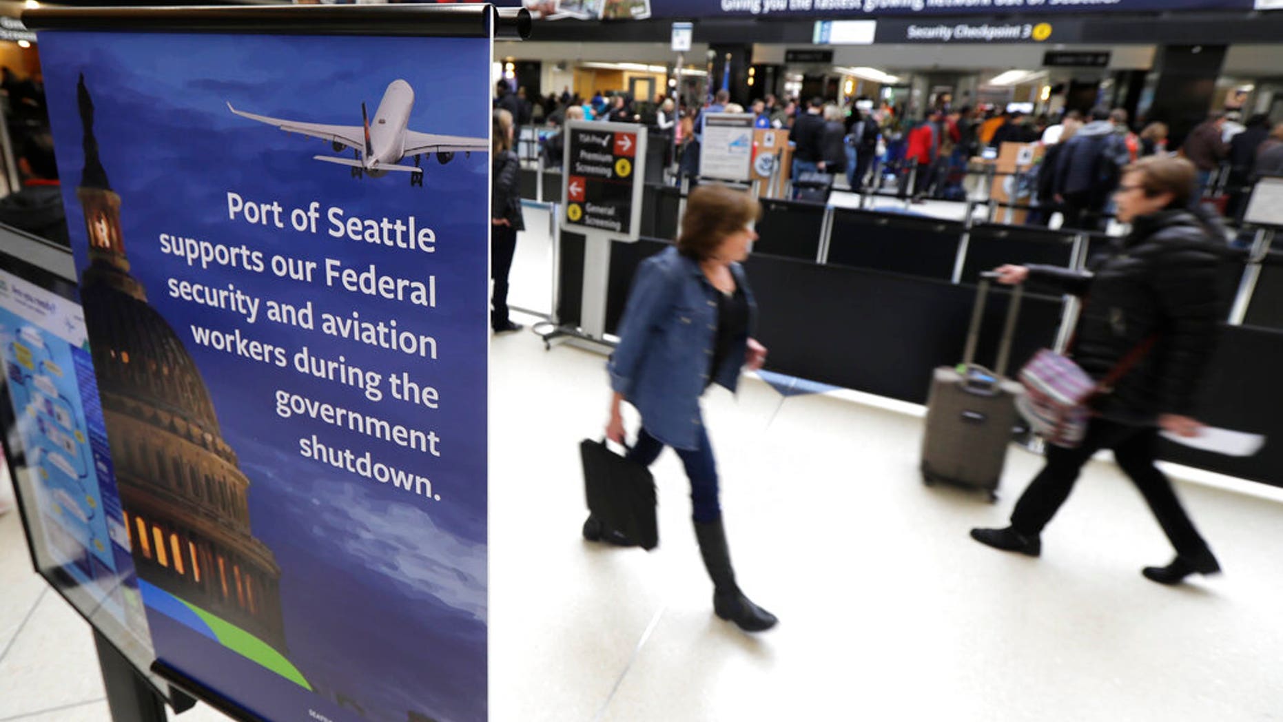 A sign near a TSA security checkpoint states the Port of Seattle's support for federal government workers, Friday, Jan. 25, 2019, in Seattle. Yielding to mounting pressure and growing disruption, President Donald Trump and congressional leaders on Friday reached a short-term deal to reopen the government for three weeks while negotiations continue over the president's demands for money to build his long-promised wall at the U.S.-Mexico border. (AP Photo/Ted S. Warren)