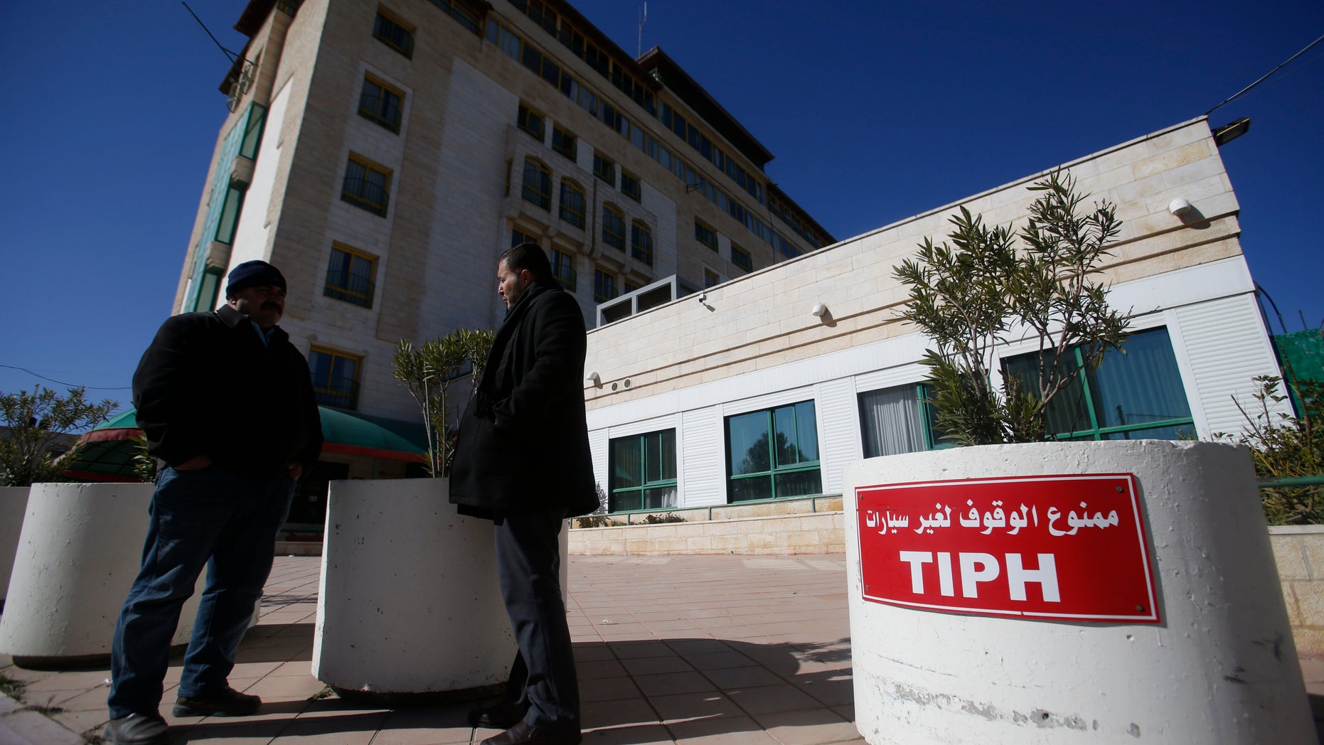Palestinians stand in front of headquarters of the Temporary International Presence in Hebron (TIPH), in the West Bank city of Hebron, Friday, Feb. 1, 2019. Israel says it is suspending operations of TIPH observer force in the occupied West Bank city of Hebron after over 20 years. (AP Photo/Majdi Mohammed)
