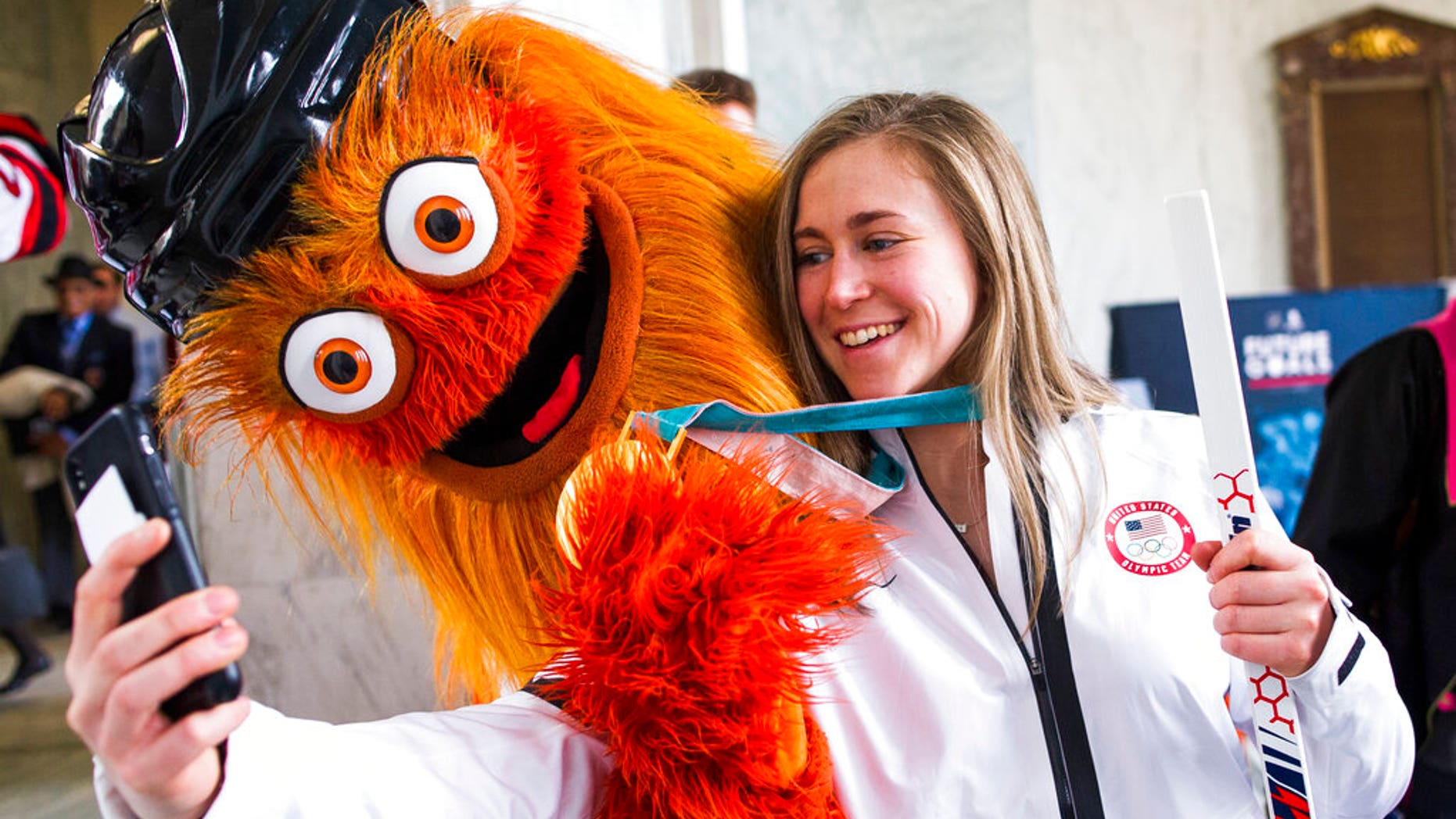 Olympic gold medalist hockey player Haley Skarupa talks a selfie with the NHL Philadelphia Flyers mascot Gritty.