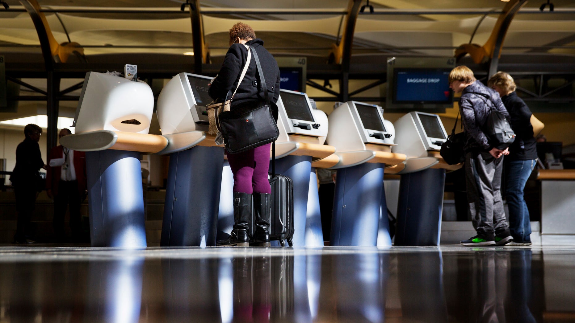In this 2017 file photo, passengers check in for Delta Air Lines flights at airport kiosks. Major U.S. airlines say they will soon change their ticketing process to give passengers an option to identifying themselves as male or female.