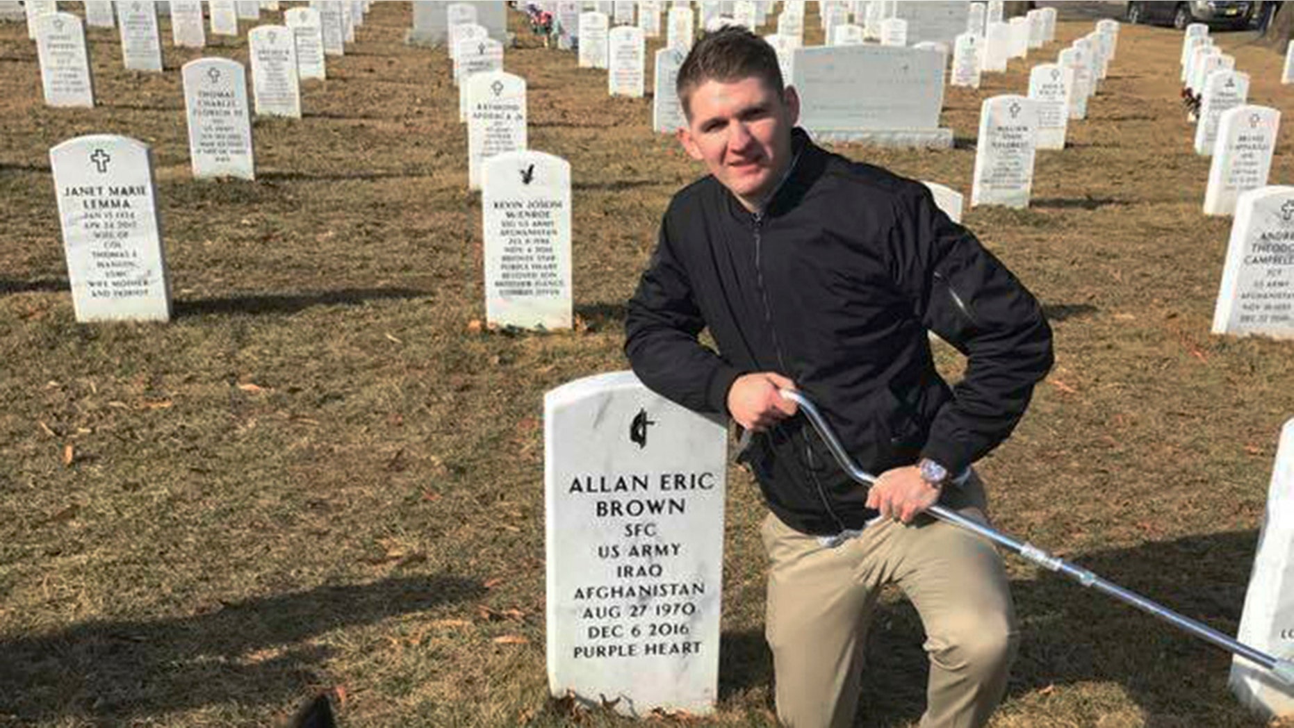 In this Jan. 30, 2018, photo provided by Vicki Hencely, her son Army Spc. Winston Hencely poses for a photo with his service dog at Arlington National Cemetery in Arlington, Va. Hencely, a U.S. soldier grievously wounded in a suicide bombing two years ago in Afghanistan, filed suit Wednesday, Feb. 20, 2019, against an American defense contractor that employed the bomber, saying it failed to supervise the man as he built an explosive vest on the job using the company's tools and parts. (Vicki Hencely via AP)