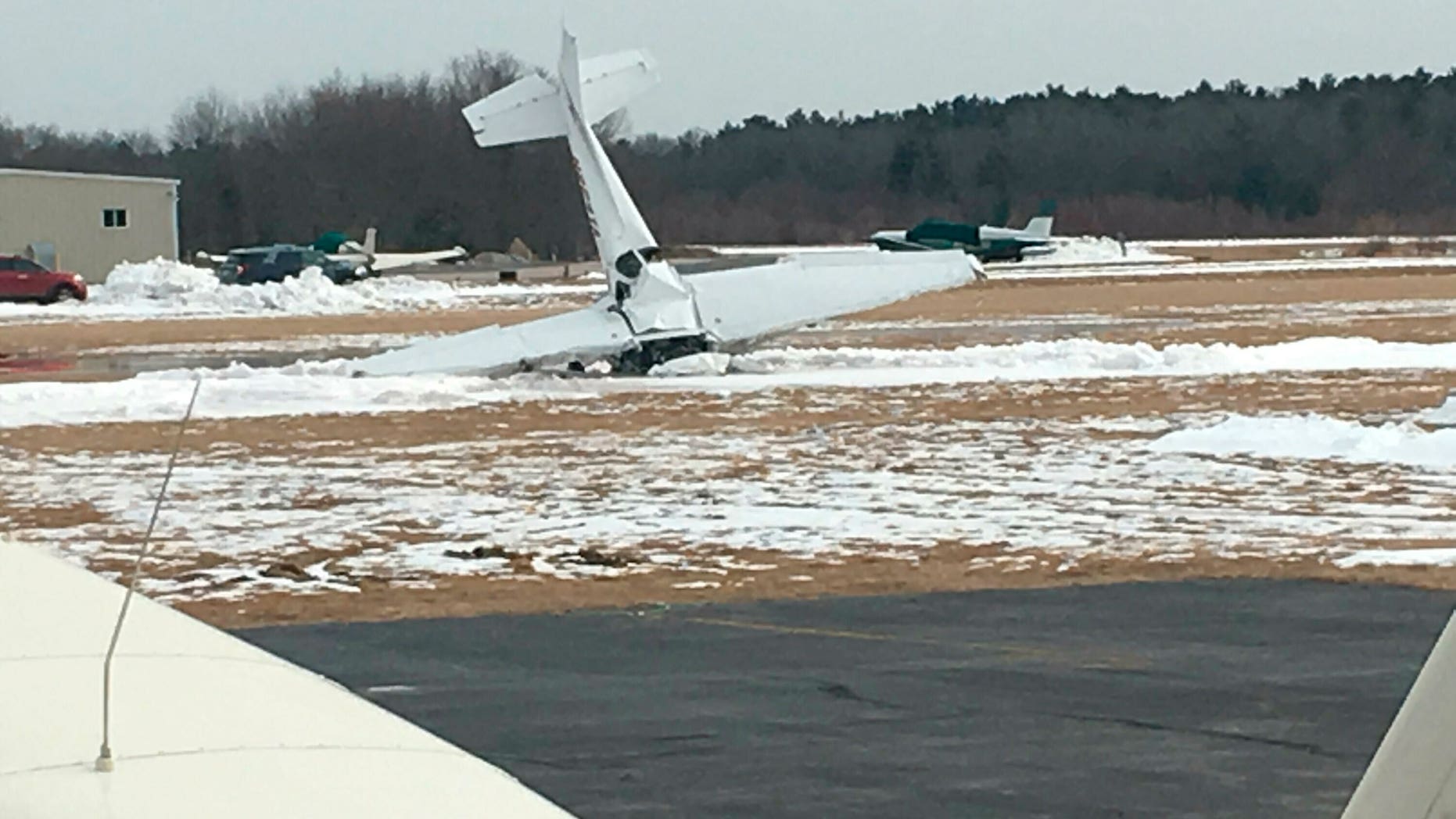 A small plane is seen resting on its nose following a crash and fire at Mansfield Municipal Airport in Mansfield, Mass., on Saturday. Massachusetts State Police confirmed that two people died in the crash, which occurred around 12:36 p.m.