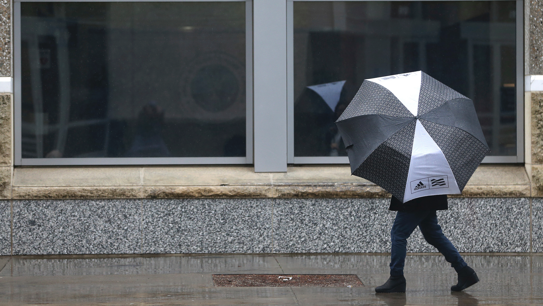 A person huddles under an umbrella as rain falls in Sacramento, Calif., Tuesday, Feb. 26, 2019. (AP Photo/Rich Pedroncelli)