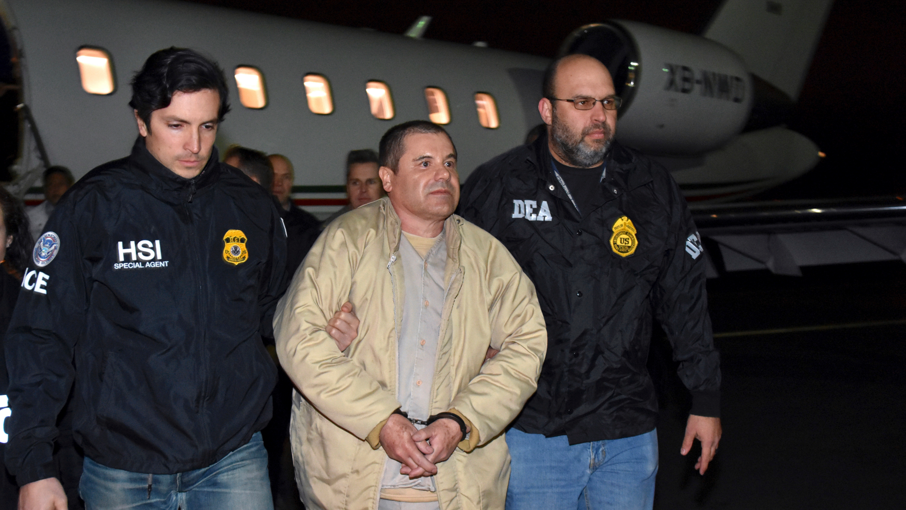 FILE - In this Jan. 19, 2017 file photo provided U.S. law enforcement, authorities escort Joaquin "El Chapo" Guzman, center, from a plane to a waiting caravan of SUVs at Long Island MacArthur Airport in Ronkonkoma, N.Y. The notorious Mexican drug lord was convicted of drug-trafficking charges, Tuesday, Feb. 12 2019, in federal court in New York. (U.S. law enforcement via AP, File)