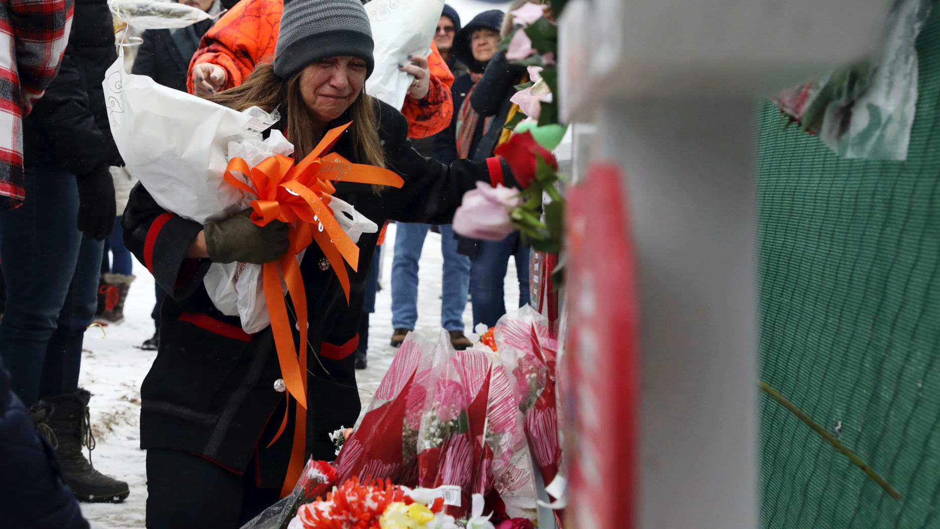 People pray at a makeshift memorial Sunday, Feb. 17, 2019, in Aurora, Ill., near Henry Pratt Co. manufacturing company where several were killed on Friday. Authorities say an initial background check five years ago failed to flag an out-of-state felony conviction that would have prevented a man from buying the gun he used in the mass shooting in Aurora. (AP Photo/Nam Y. Huh)