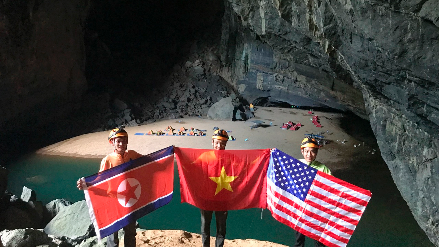 In this Monday, Feb. 15, 2019, drone image, cave explores pose with flags of North Korea, Vietnam and the U.S. in En cave in Quang Binh province, Vietnam. Vietnam will host the second summit between U.S. President Donald Trump and North Korean leader Kim Jong Un in Hanoi on Feb. 27-28. (Oxalis Adventure via AP)