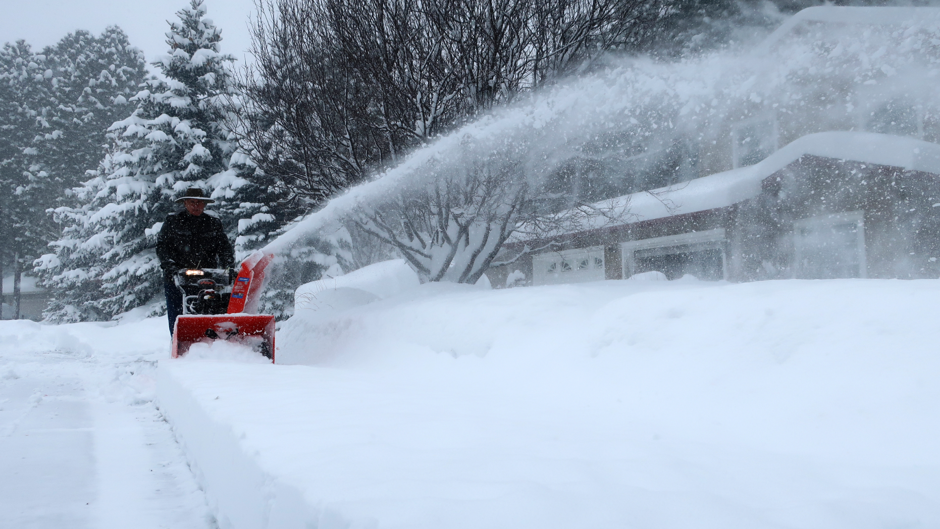 Richard Henn runs a snow blower down the sidewalk outside his home in Flagstaff, Arizona, on Thursday, Feb. 21, 2019. Schools across northern Arizona canceled classes and some government offices decided to close amid a winter storm that's expected to dump heavy snow in the region. (AP Photo/Felicia Fonseca)