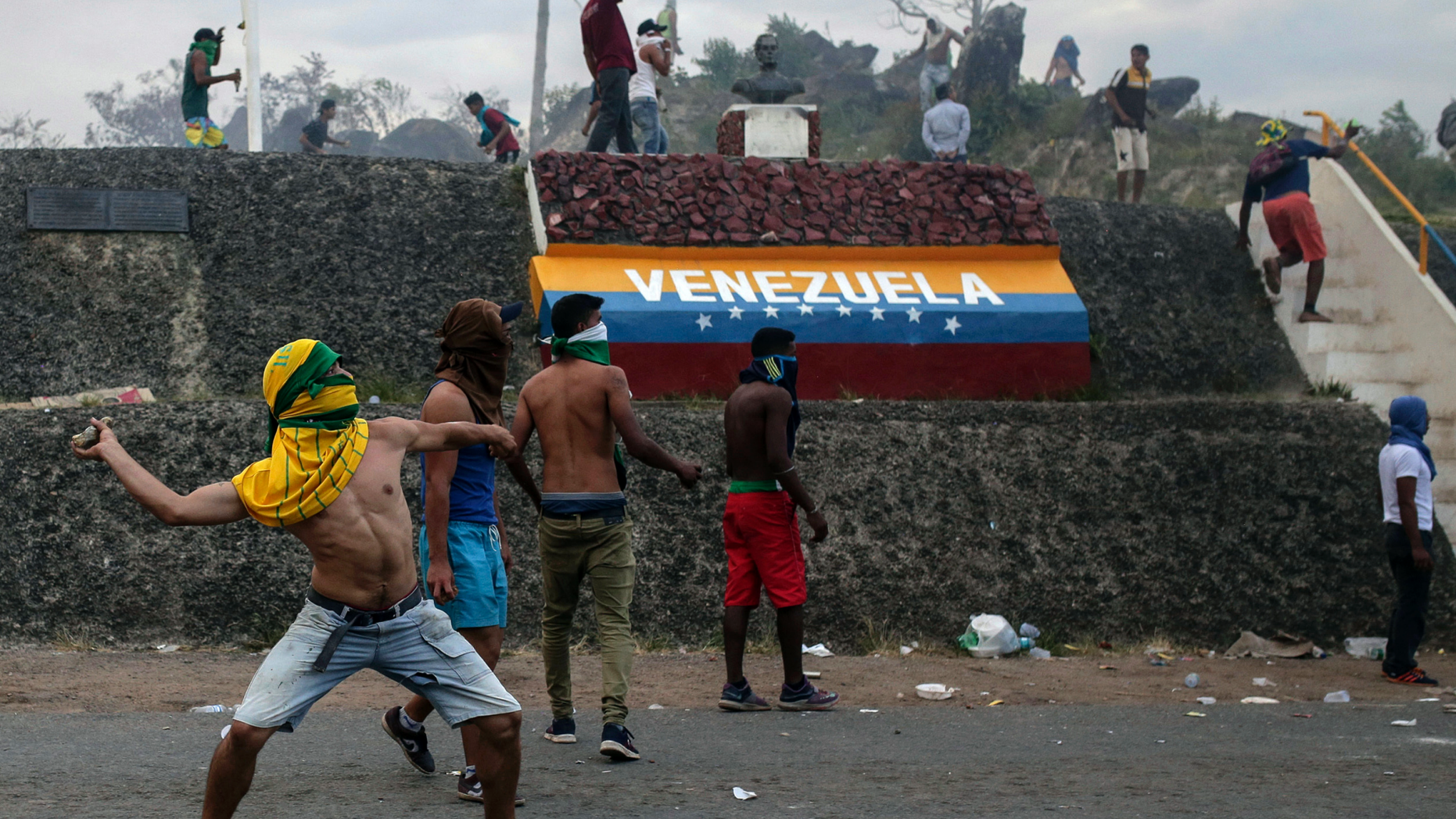 Venezuelan demonstrators throw stones during clashes with authorities, at the border between Brazil and Venezuela, Saturday, Feb.23, 2019. Tensions are running high in the Brazilian border city of Pacaraima. Thousands remained at the city's international border crossing with Venezuela to demand the entry of food and medicine.(AP Photo/Ivan Valencia)