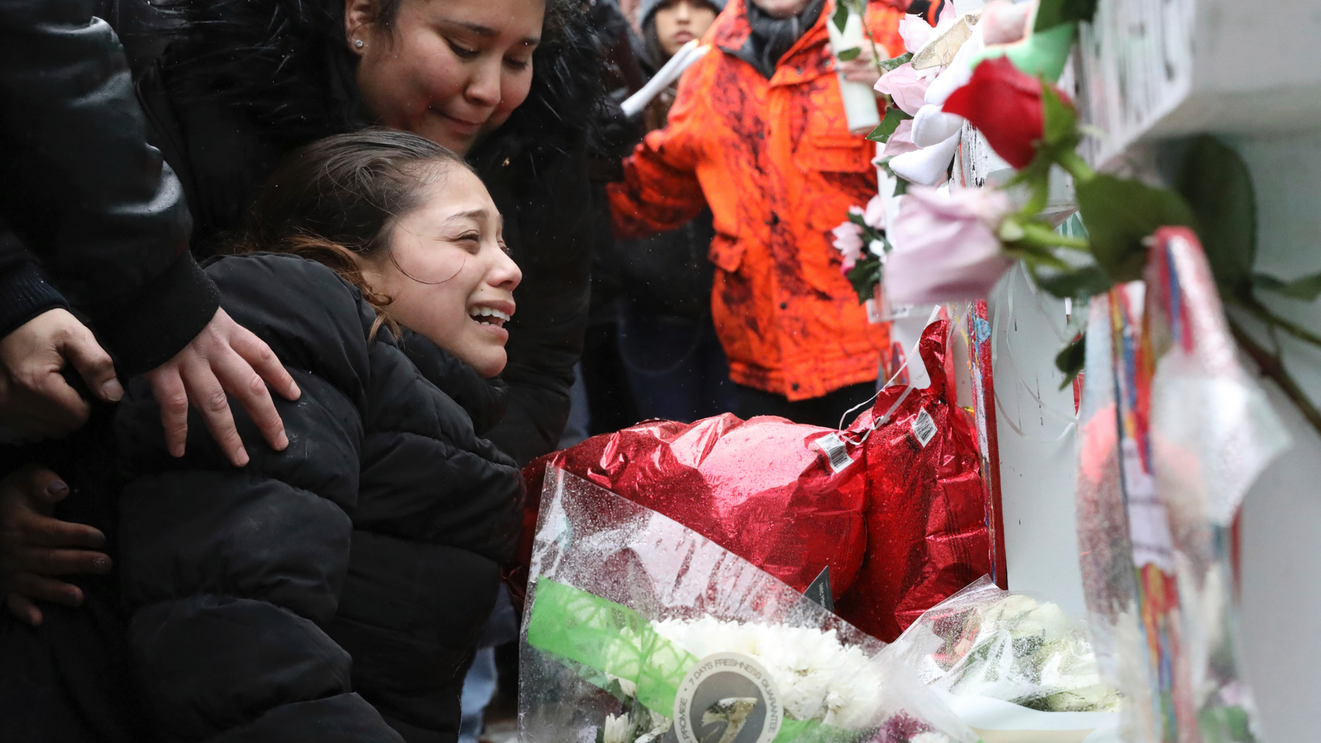 One of victim Vicente Juarez's daughter Diana Juarez cries at a makeshift memorial Sunday, Feb. 17, 2019, in Aurora, Ill., near Henry Pratt Co. manufacturing company where several were killed on Friday. Authorities say an initial background check five years ago failed to flag an out-of-state felony conviction that would have prevented a man from buying the gun he used in the mass shooting in Aurora. (AP Photo/Nam Y. Huh)