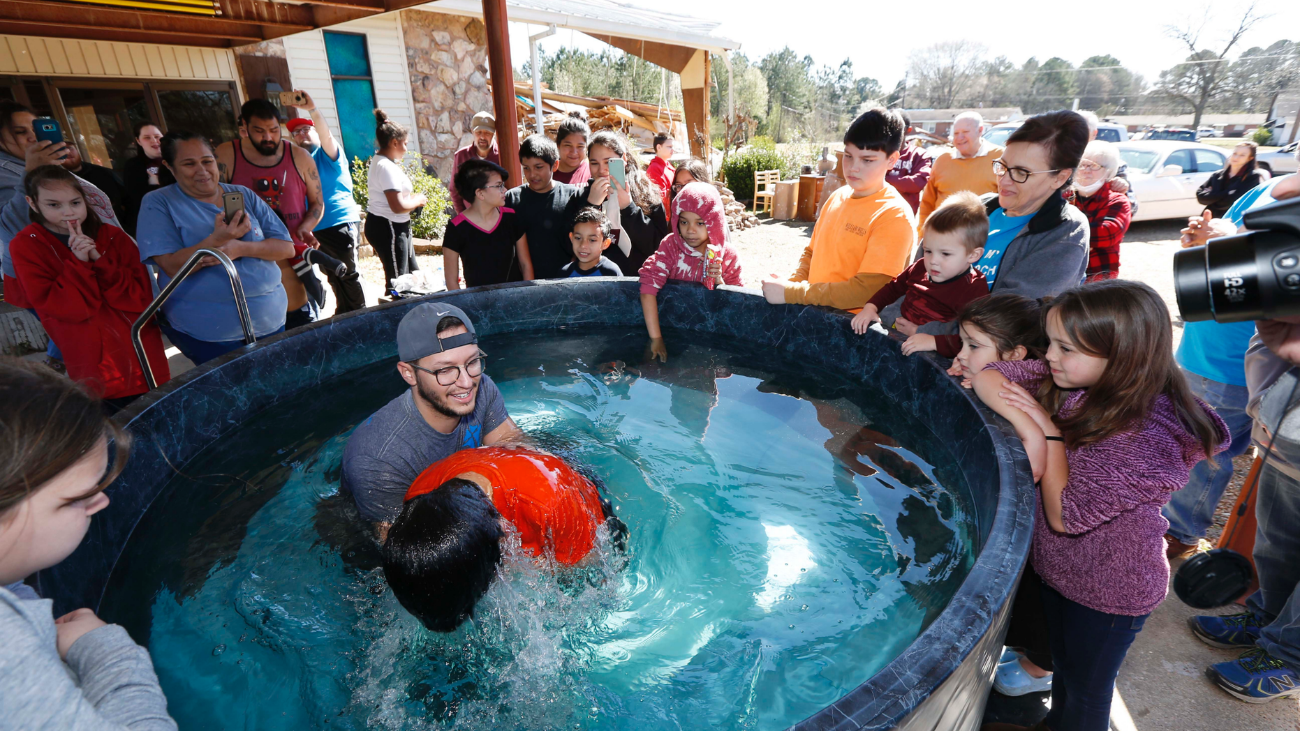 Church members watch as student pastor Craig Blaylock, left, baptizes a church member at the First Pentecostal Church in Columbus, Miss., Sunday morning, Feb. 24, 2019. The church, in the background, was destroyed by a tornado Saturday afternoon, but church members opted to go ahead with the baptisms as planned. (AP Photo/Rogelio V. Solis)