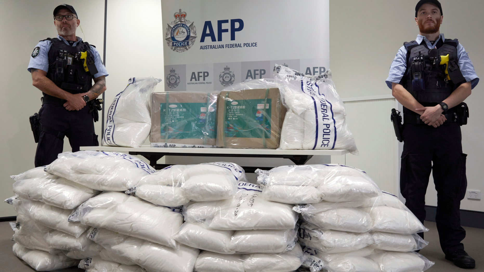 Police guard some of the 1.4 tons of seized ephedrine that is piled up during an Australian Federal Police press conference in Melbourne, Wednesday, Feb. 27, 2019. Australian authorities say they seized chemicals which could have been used to make one ton of methamphetamine and arrested four men in a joint operation with China. (Erik Anderson/AAP Image via AP)