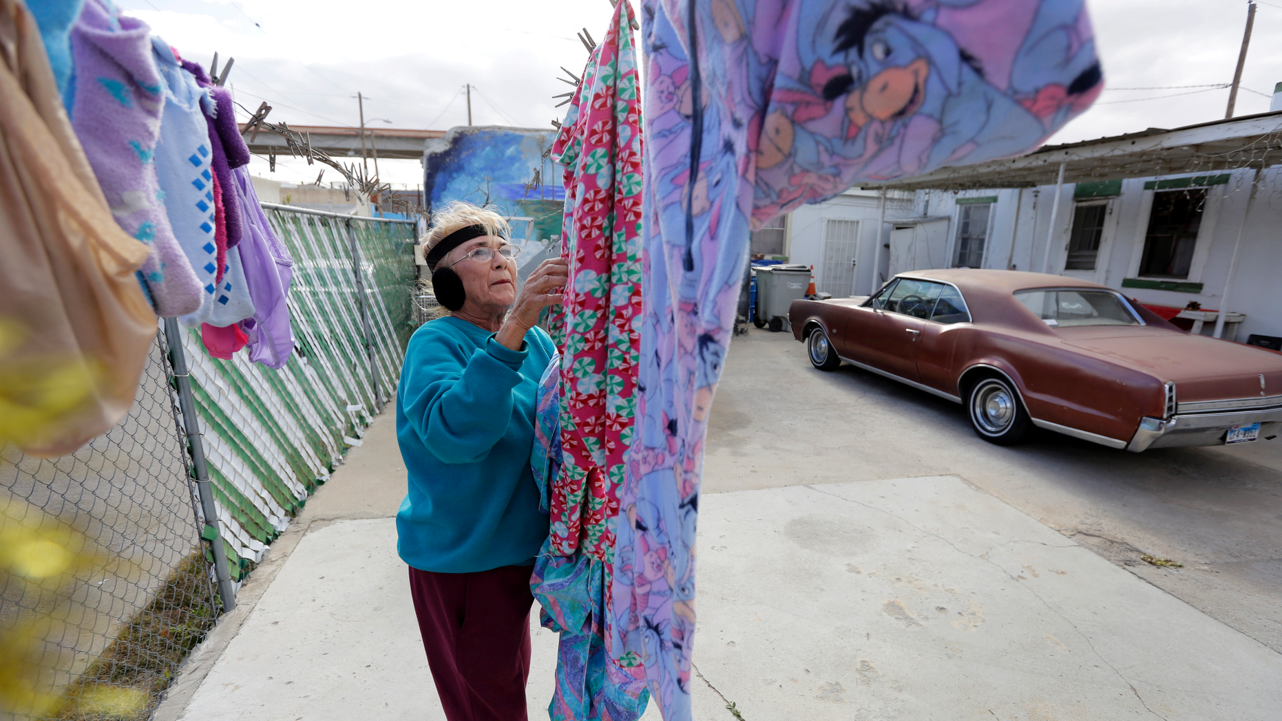 In this Tuesday, Jan. 22, 2019, photo, Mickie Subia gathers her laundry at her home in El Paso, Texas. Subia lives less than a block away from a border barrier that runs along the Texas-Mexico border in El Paso. (AP Photo/Eric Gay)
