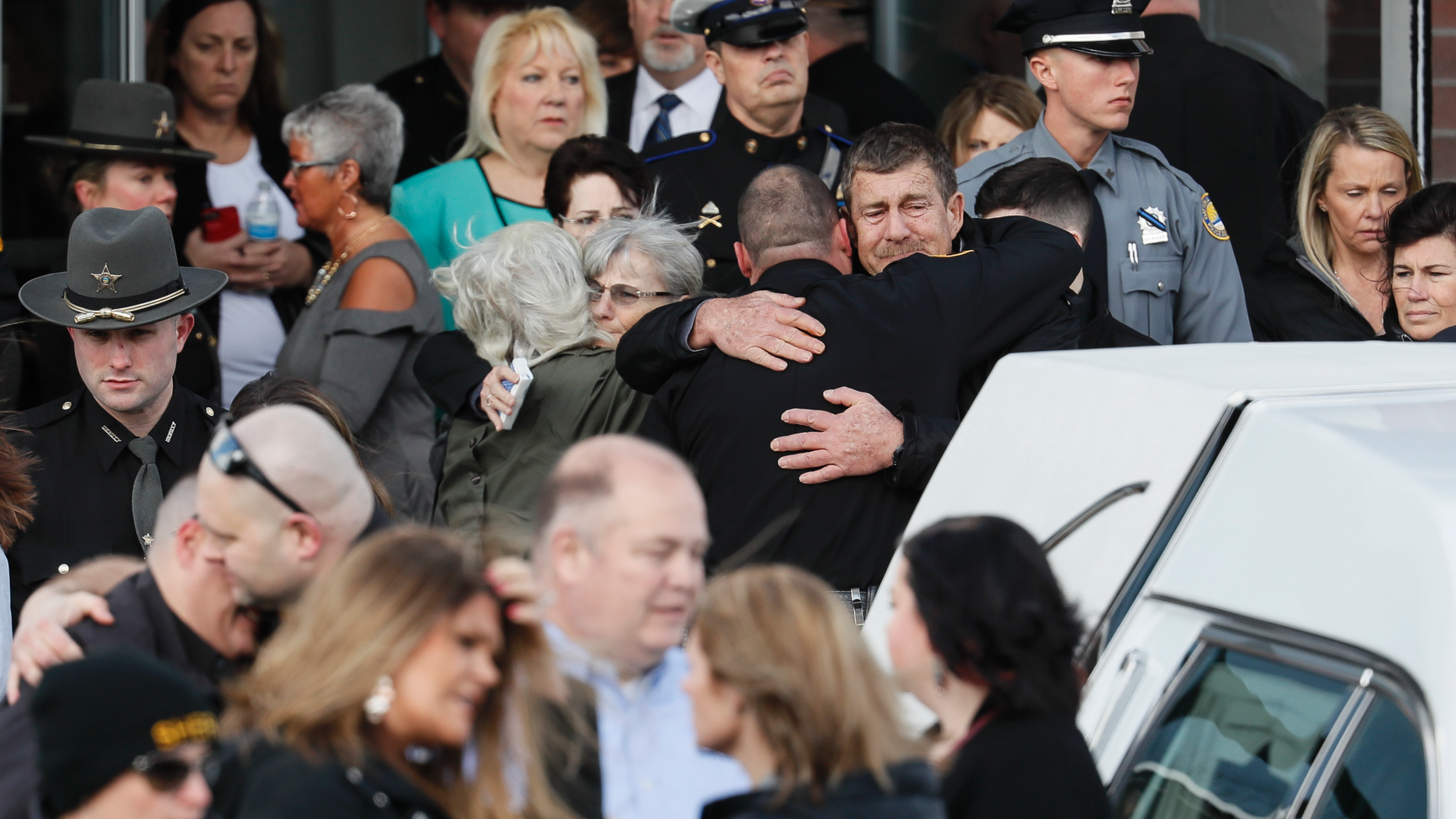 Officers and mourners react after the casket of Detective Bill Brewer, a 20-year veteran of the Clermont County Sheriff's Office, is placed into a hearse outside of Mt. Carmel Christian Church during funeral ceremonies, Friday, Feb. 8, 2019, in Batavia, Ohio. Authorities in the Cincinnati region are reeling after the deaths of five police officers in less than two months. (AP Photo/John Minchillo)