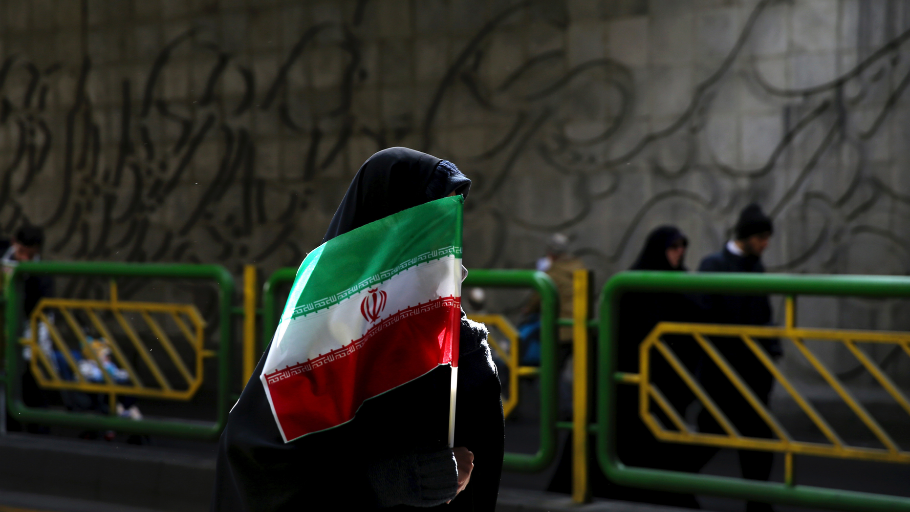 FILE - In this Feb. 11, 2016 file photograph, an Iranian woman holds the national flag during a rally commemorating the 37th anniversary of the Islamic revolution, in Tehran, Iran. Iran's 1979 Islamic Revolution initially inspired both Islamic militants and Islamists across the Mideast. They saw the revolution as the starting gun in a competition to push out the strongman Arab nationalism that had taken hold across the Middle East. However, analysts say Iran's push to back militants in the wider Mideast and Saudi Arabia's efforts to mobilize the Sunni world against the Shiite power would turn many away. (AP Photo/Ebrahim Noroozi, File)