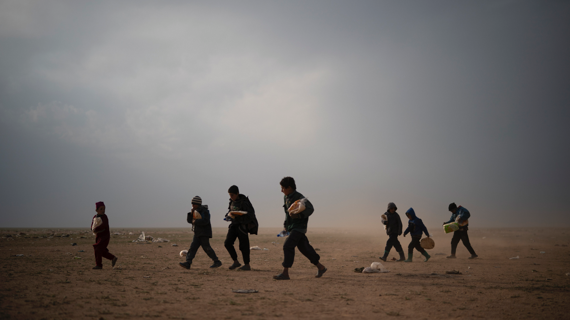 Children evacuated out of the last territory held by Islamic State militants walk at a screening center after collecting food, outside Baghouz, Syria, Tuesday, Feb. 26, 2019. Evacuations have continued amid a standoff between the militants and the U.S.-backed Syrian Democratic Forces (SDF). (AP Photo/Felipe Dana)