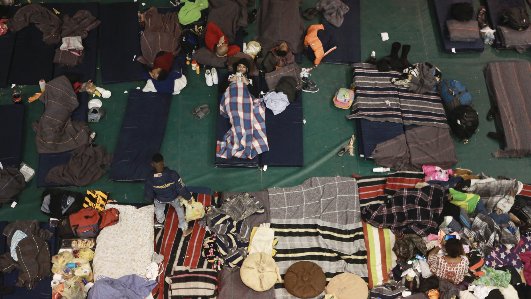In this Tuesday, Feb. 19, 2019 photo, migrants from Central America, Africa and the Caribbean, who are awaiting their turns to request asylum in the U.S., pass the time inside a shelter in Bachilleres gymnasium in Ciudad Juarez, Mexico. Hundreds of migrants, some of whom arrived from the recently closed shelter in Piedras Negras on the Mexico-U.S. border, are camped out in the gym waiting their chance to submit their asylum request at the El Paso port of entry. (AP Photo/Christian Torres)