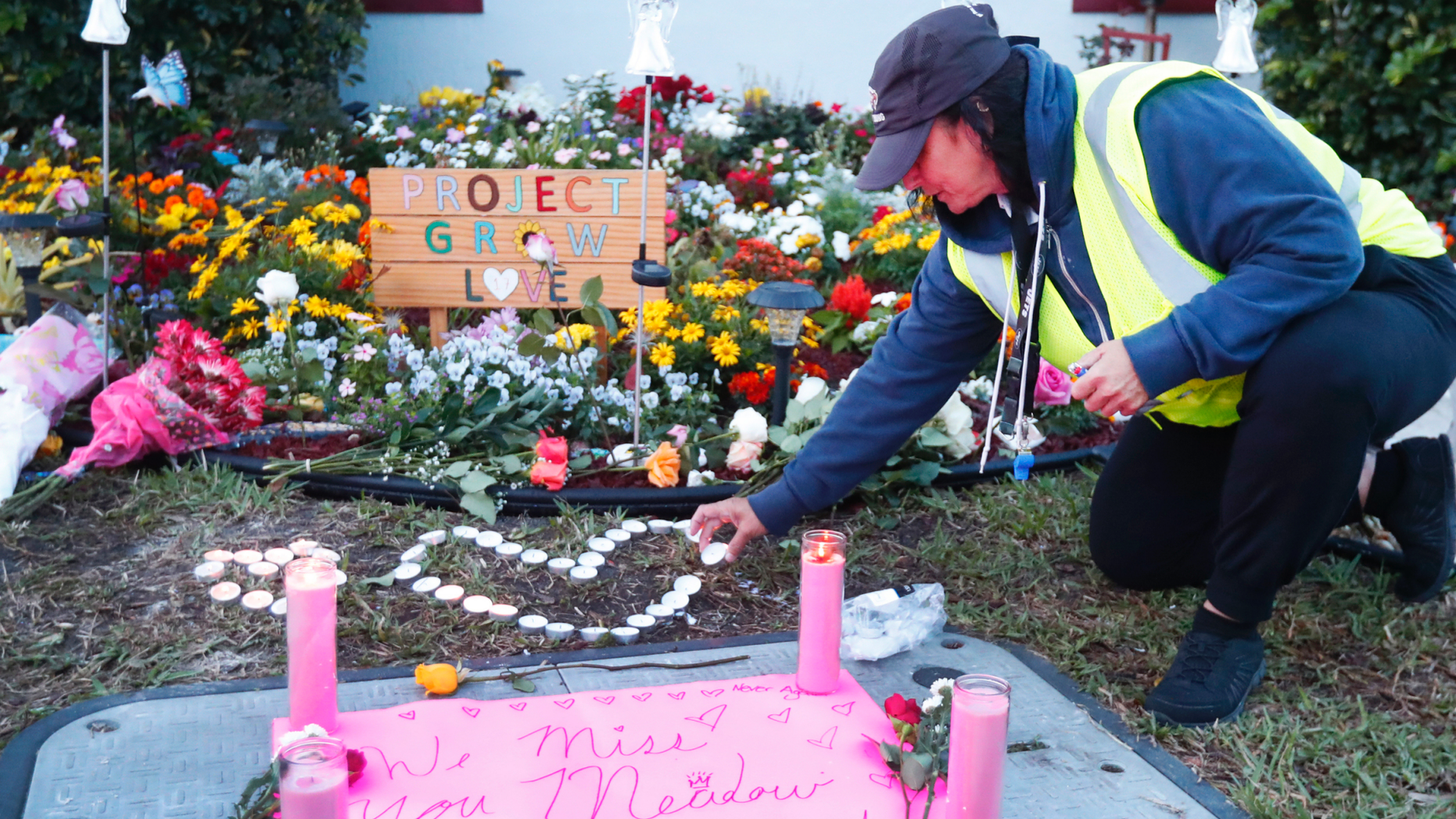 School crossing guard Wendy Behrend lights a candle at a memorial outside Marjory Stoneman Douglas High School during the one-year anniversary of the school shooting, Thursday, Feb. 14, 2019, in Parkland, Fla. A year ago on Thursday, 14 students and three staff members were killed when a gunman opened fire at the high school. (AP Photo/Wilfredo Lee)