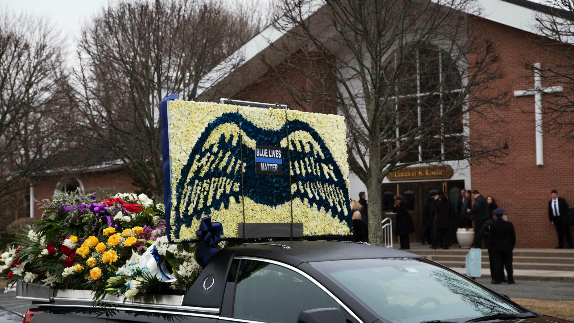 A limousine that is part of the funeral procession for Det. Brian Simonsen, is parked in front of the Church of St. Rosalie in Hampton Bays, N.Y., Wednesday, Feb. 20, 2019. Simonsen, with the New York City Police Department, was killed by friendly fire Feb. 12 as he and six other officers opened fire on a robbery suspect who police say was pointing at them what appeared to be a handgun. (AP Photo/Mark Lennihan)